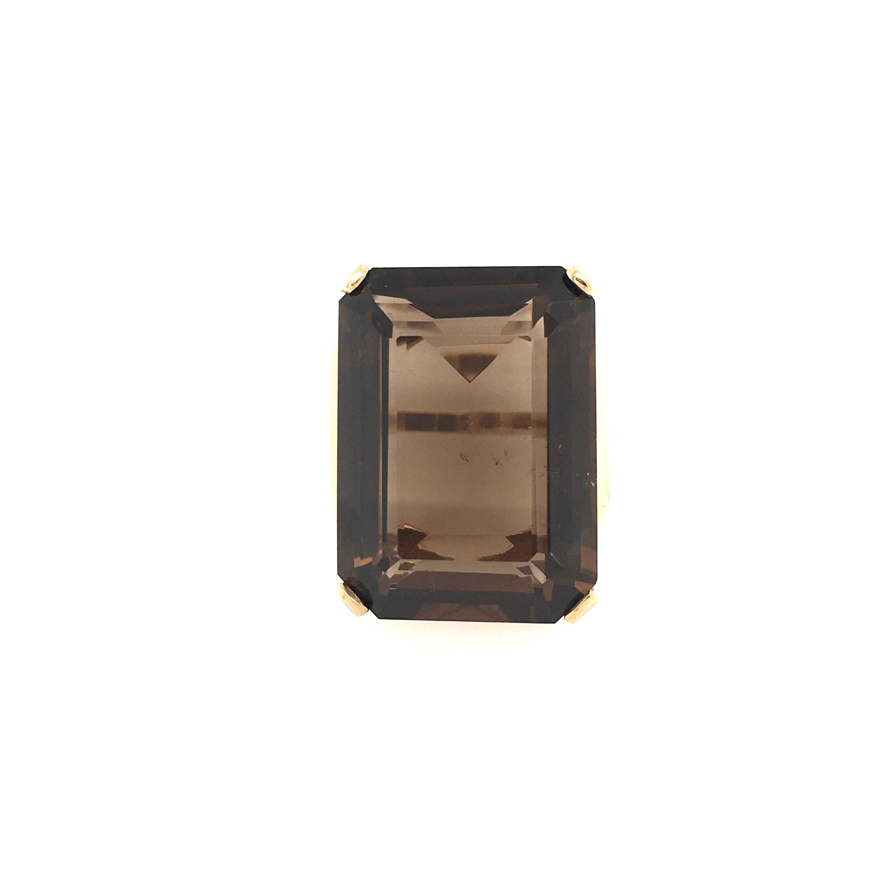 A 14 karat yellow gold and smoky quartz ring. Set with an emerald cut smoky quartz, measuring approximately 24.0 x 18.0mm, with curved shoulders. Size 7, gross weight is approximately 14.2 grams.