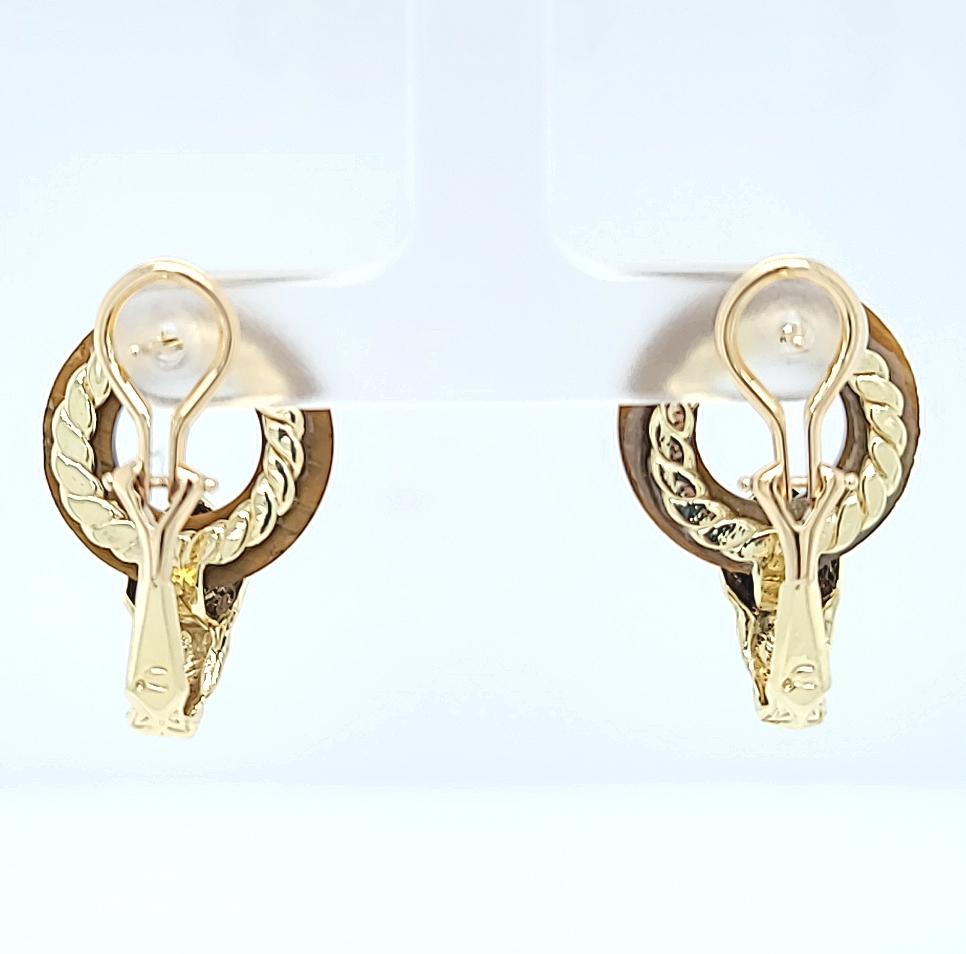 Orecchini in oro giallo 14 carati con anello a occhio di tigre intagliato e accenti angolari in oro. Perno traforato con fondello a clip Omega. Post rimosso su richiesta. Il peso finito è di 11.0 grammi.