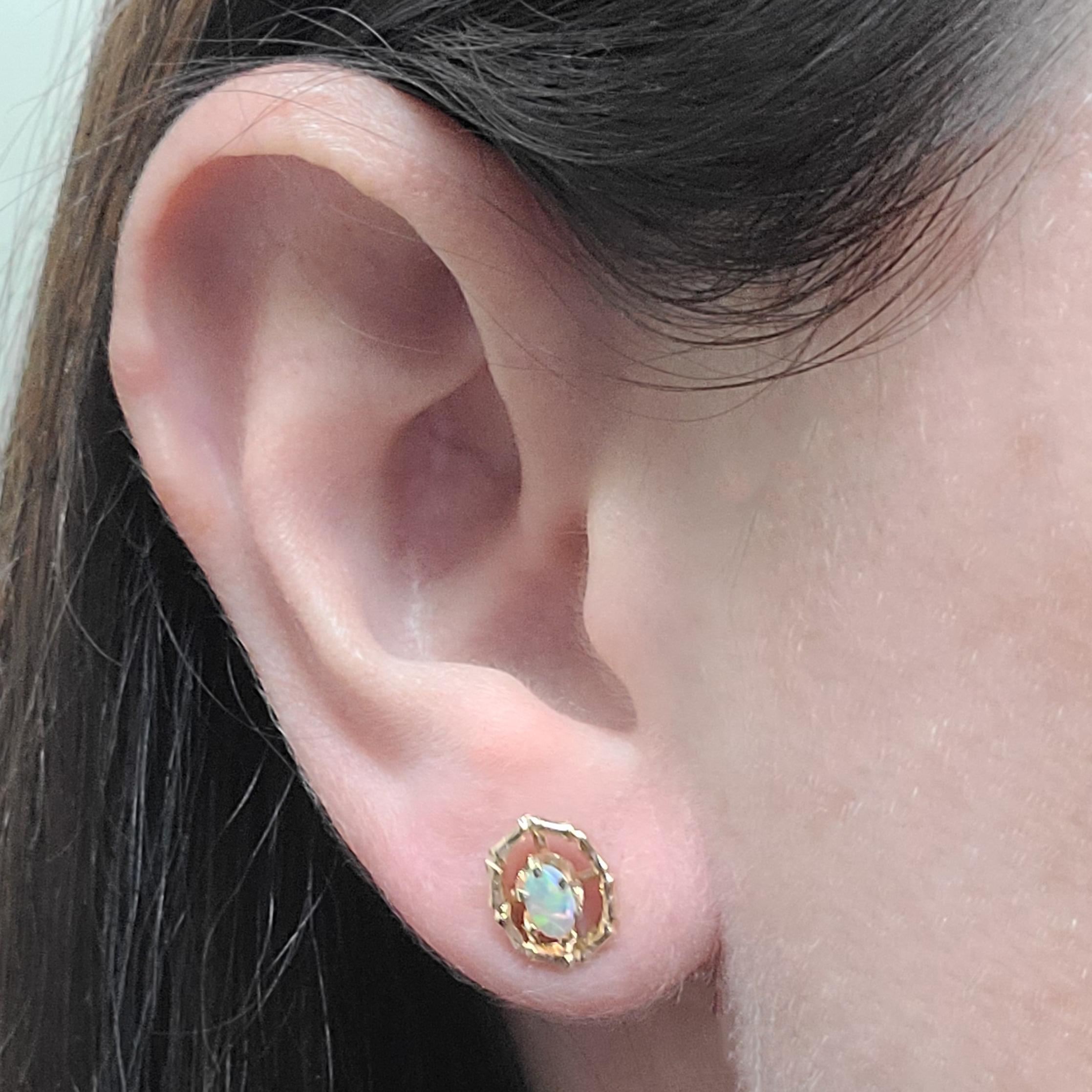 14 Karat Yellow Gold Stud Earrings Featuring Oval Cabochon Opals Surrounded By A Bamboo Texture Gold Halo. Pierced Post With Friction Back. Finished Weight Is 2.0 Grams.