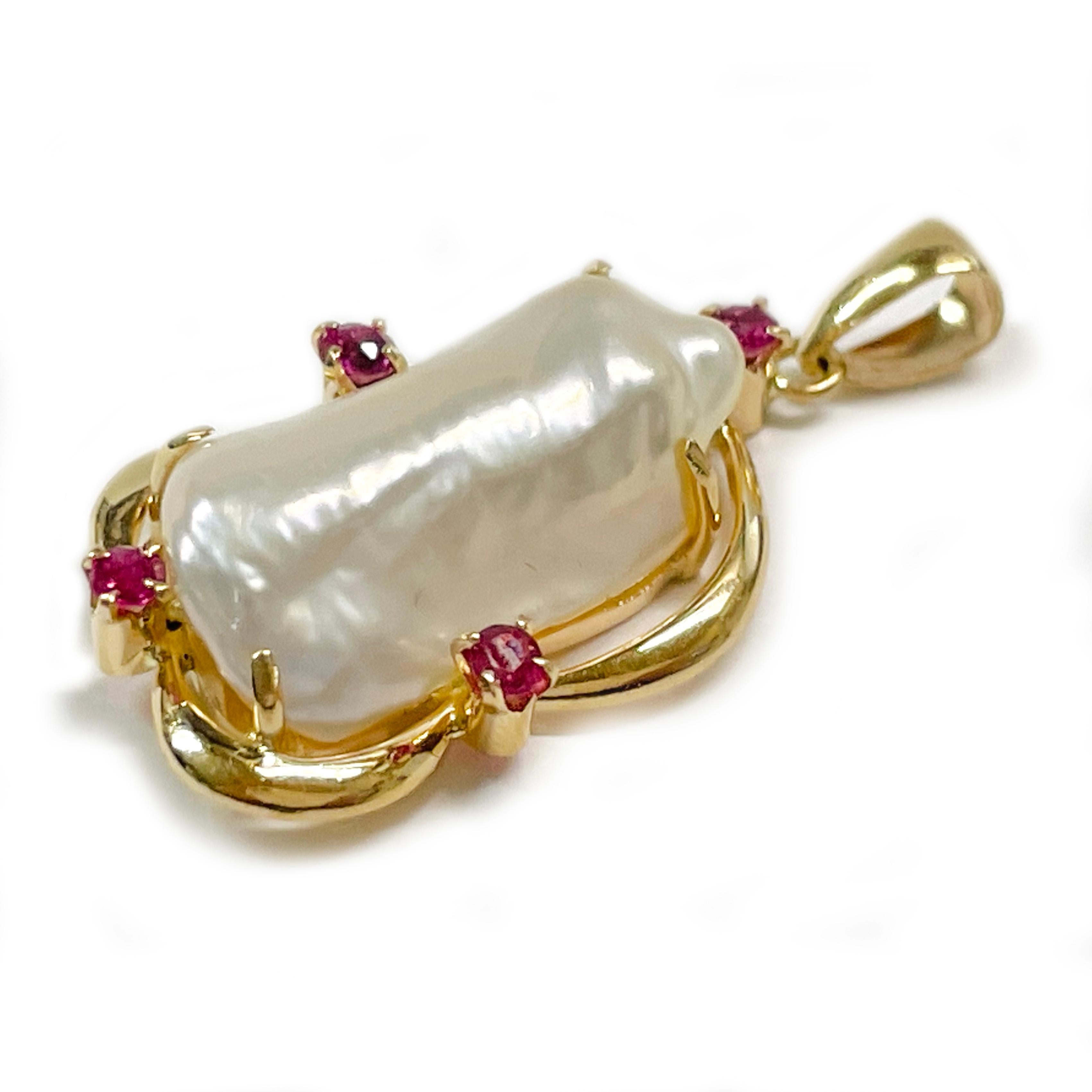 Pendentif en or jaune 14 carats, perle baroque et rubis. Le pendentif présente une eau douce baroque blanche sertie sur un chaton ouvert avec quatre rubis ronds sertis. La perle présente un bon lustre et de légères nuances de rose et de bleu/vert.