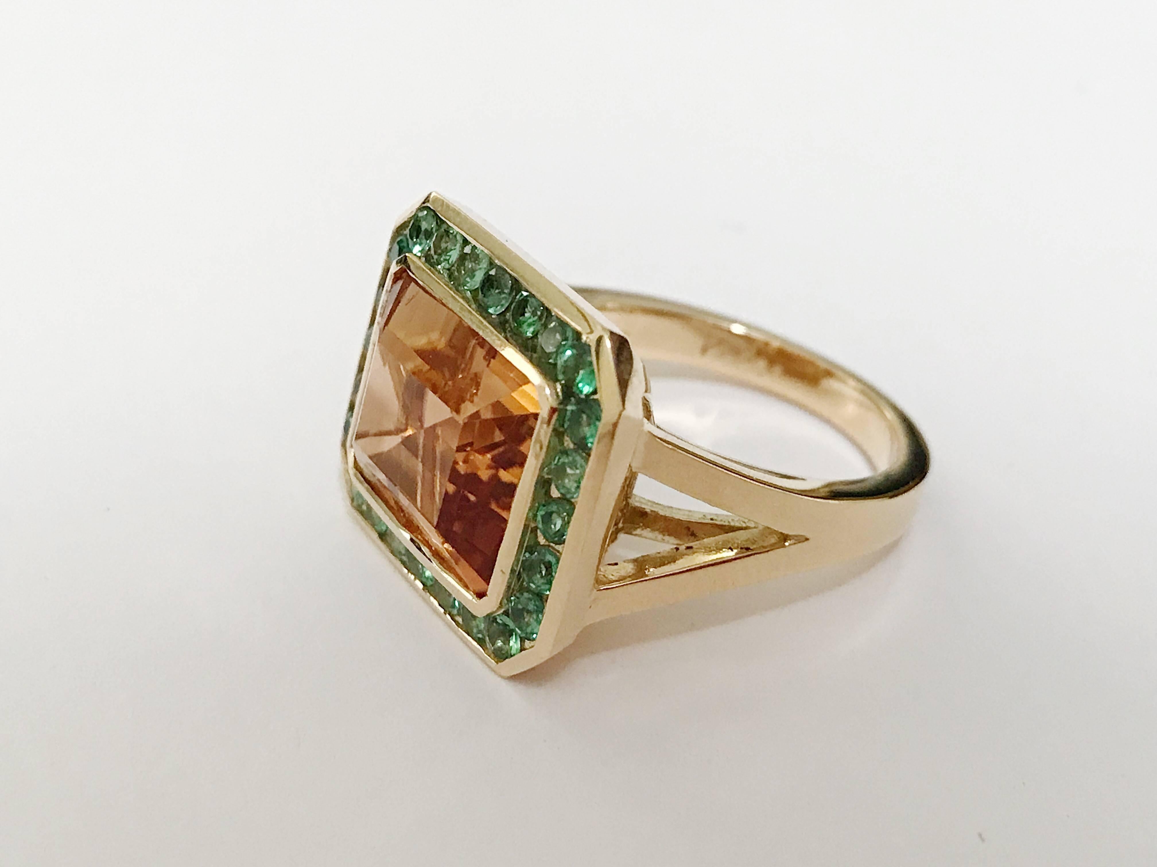 18kt Yellow Gold and Split Shank Ring with Emerald Cut Citrine Center Stone with surrounding Tsvaorite is an elegant cocktail ring. Measures 0.75 across the top.

This Ring can be made with any color center stone as well as type of surrounding