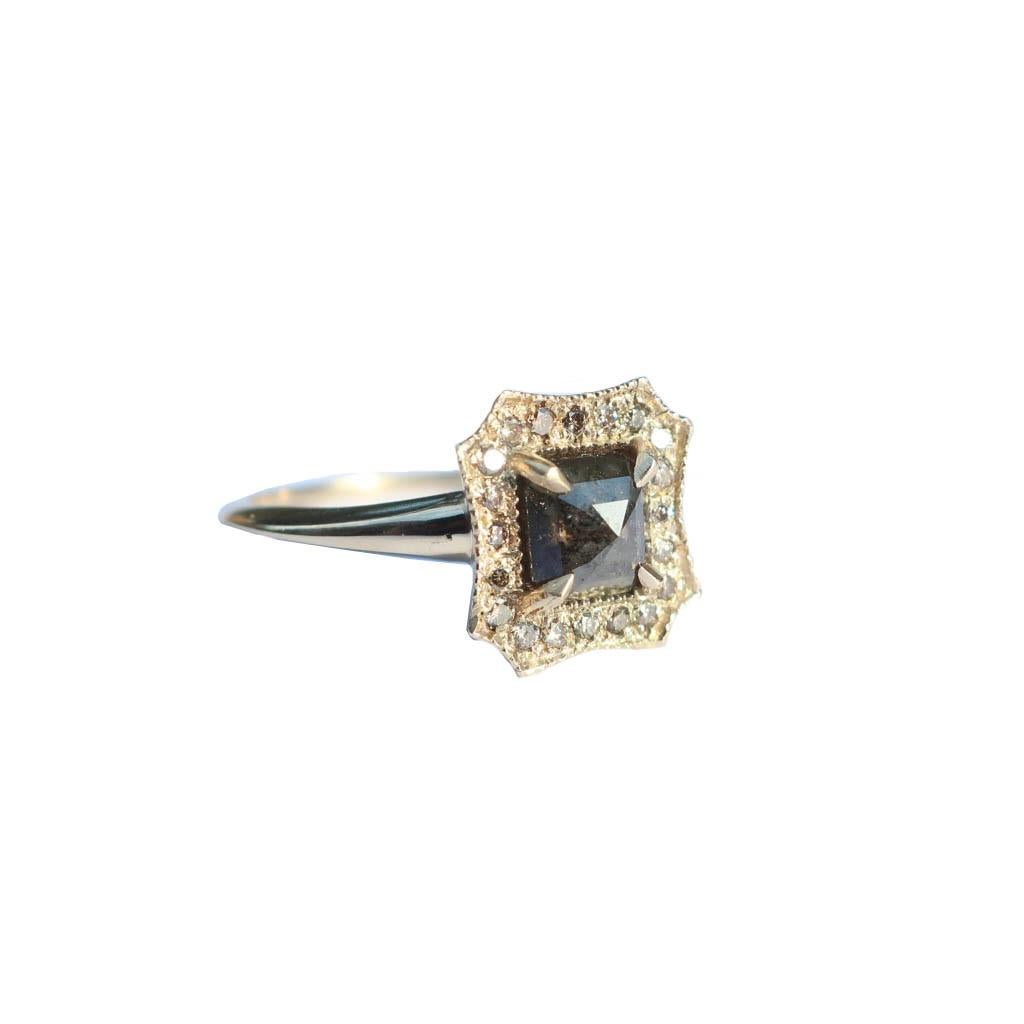 This regal ring showcases a rosecut grey diamond claw set in 14k yellow gold. The band tappers elegantly to the back with a knife edge band.  A halo of champagne diamonds surrounds this .99 center stone. 

Size 7- Can be resized upon request