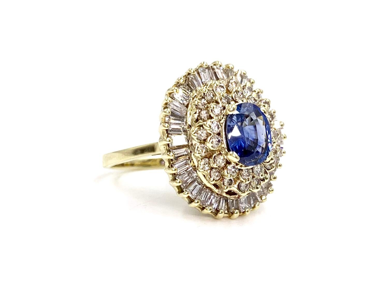 Vintage 14 karat yellow gold blue sapphire and diamond cluster style cocktail ring. Ring features a beautiful oval blue sapphire center, approximately 1 carat surrounded by approximately 1.60 carats of round brilliant diamonds and an outer halo of