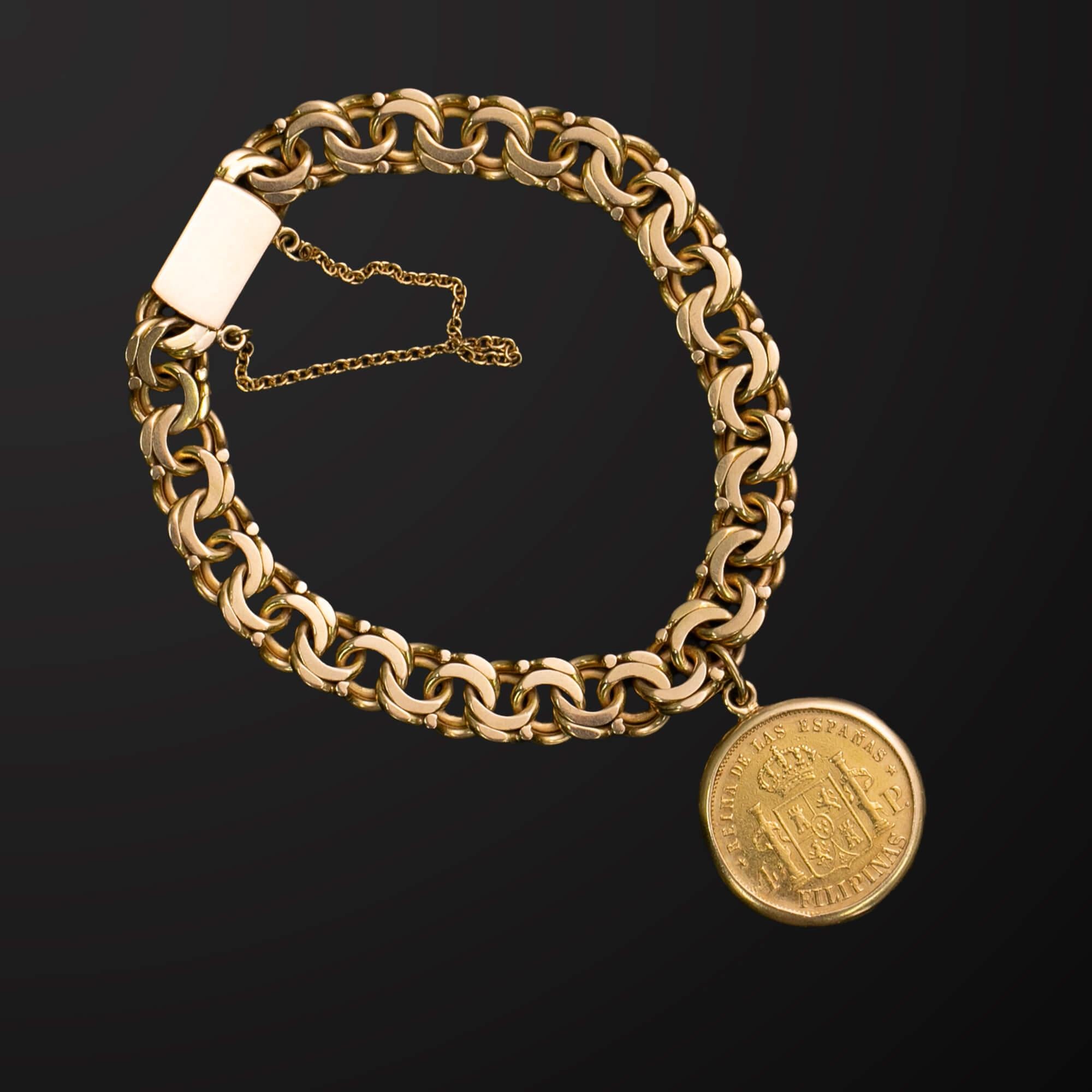 Pulsera de eslabones de fantasía de oro amarillo de 18 quilates con una moneda engastada en bisel como amuleto destacado. La moneda es una de 1868, 4 pesos ceca de Manila (Filipinas), Isabell II. La pulsera se sujeta con un cierre de caja y una