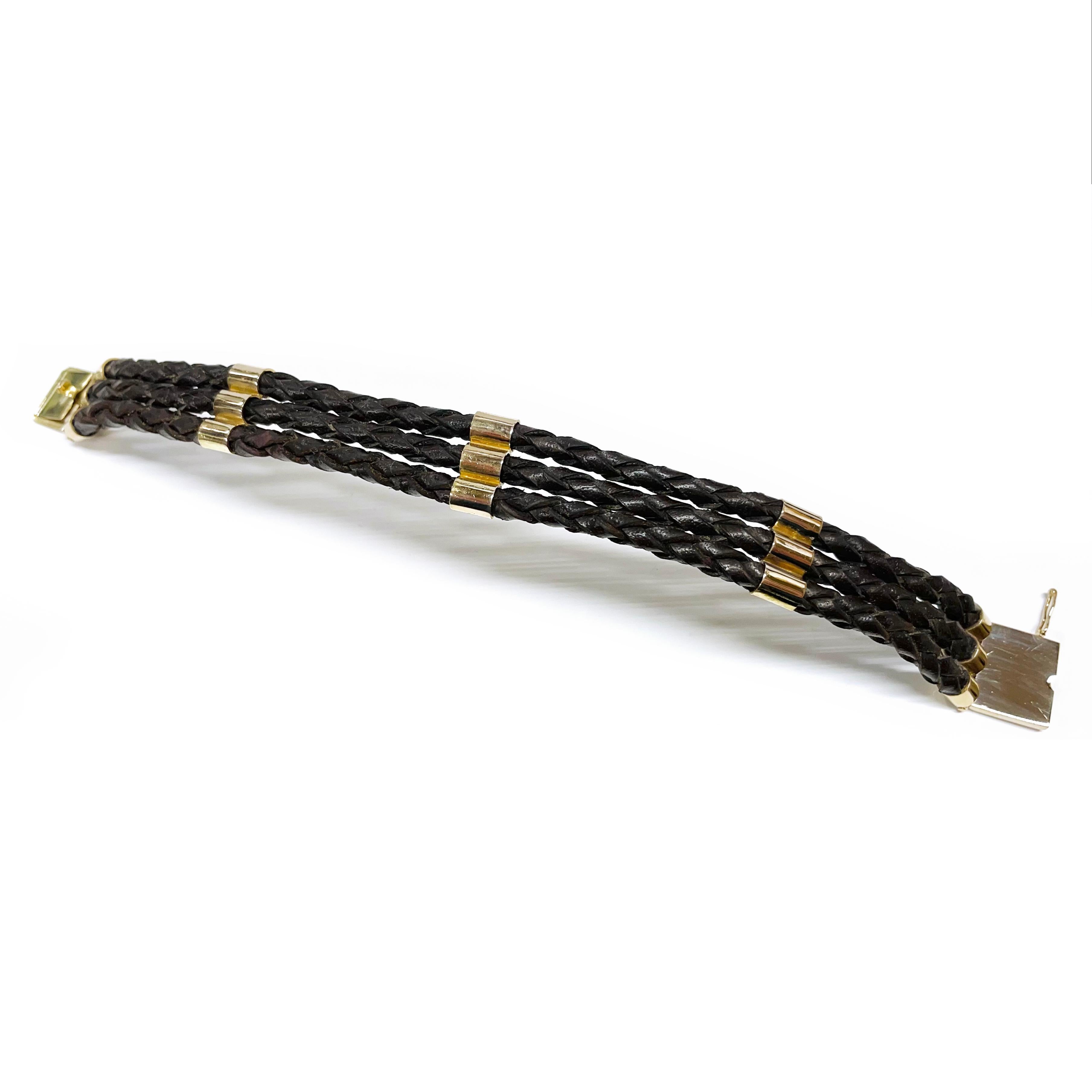 14 Karat Yellow Gold Braided Leather Three-Strand Bracelet. The handcrafted bracelet features three braided brown leather strands with three gold accents and gold accent ends with tongue and box clasp closure and a safety eight. Stamped on the