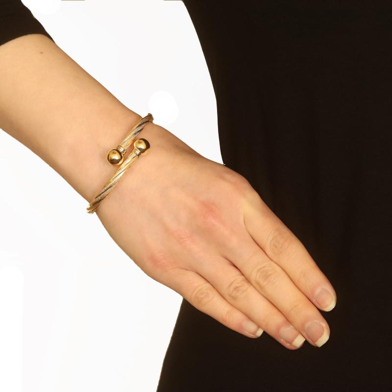 Metal Content: 18k Yellow Gold & 18k White Gold

Style: Bypass Bangle
Fastening Type: Hinge
Theme: Rope Twist
Features: Hollow Construction with Smooth & Textured Finishes

Measurements
Inner Circumference: 6 1/2