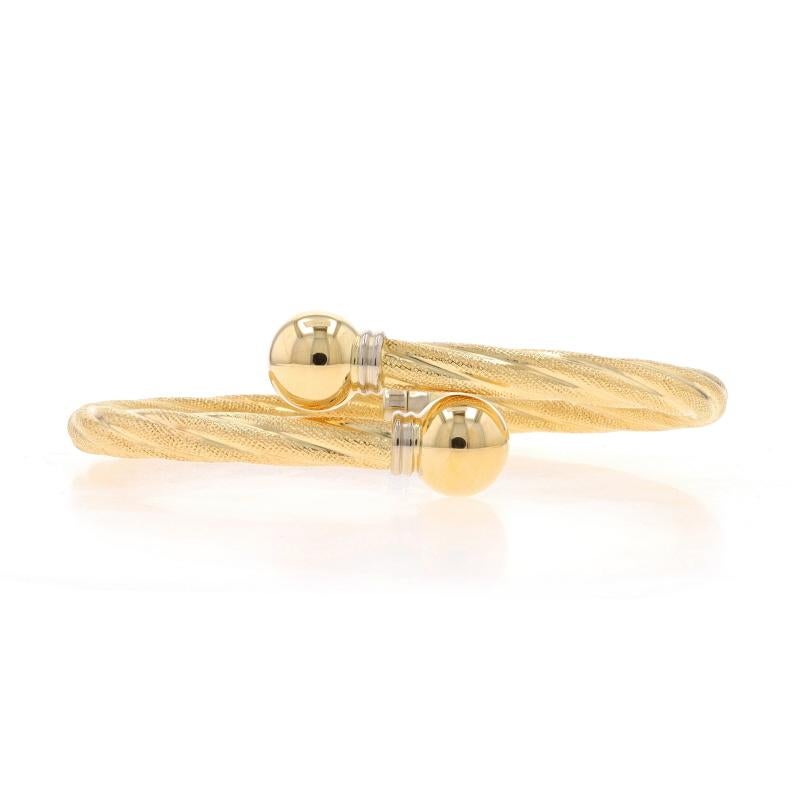 Metal Content: 18k Yellow Gold & 18k White Gold

Style: Bypass Bangle
Fastening Type: Hinge
Theme: Rope Twist
Features: Hollow Construction with Smooth & Textured Finishes

Measurements
Inner Circumference: 6 1/2
