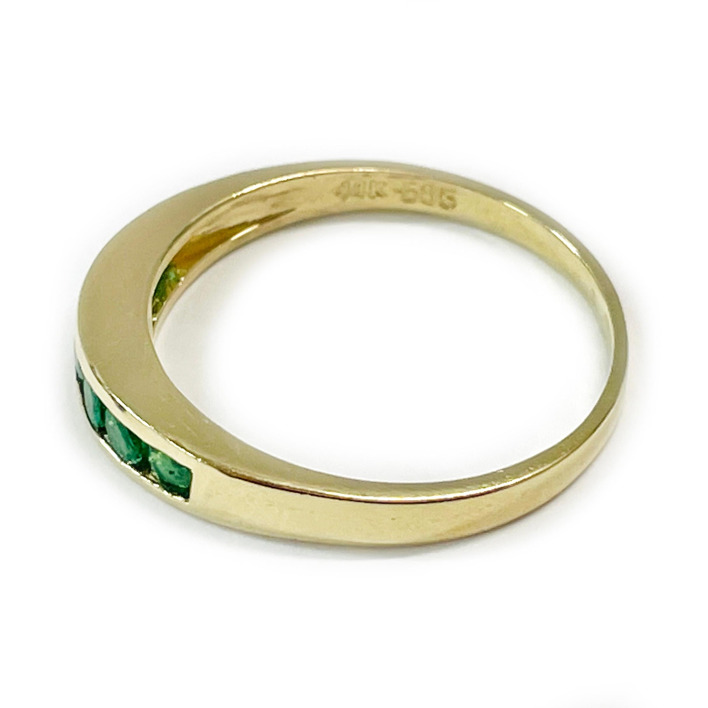 14 Karat Yellow Gold Channel-Set Emerald Ring. The ring features six 3.1mm round channel-set green emeralds. The total weight of the emeralds are 0.66ctw. The ring has a smooth shiny finish with a slight taper. Stamped on the inside of the band are