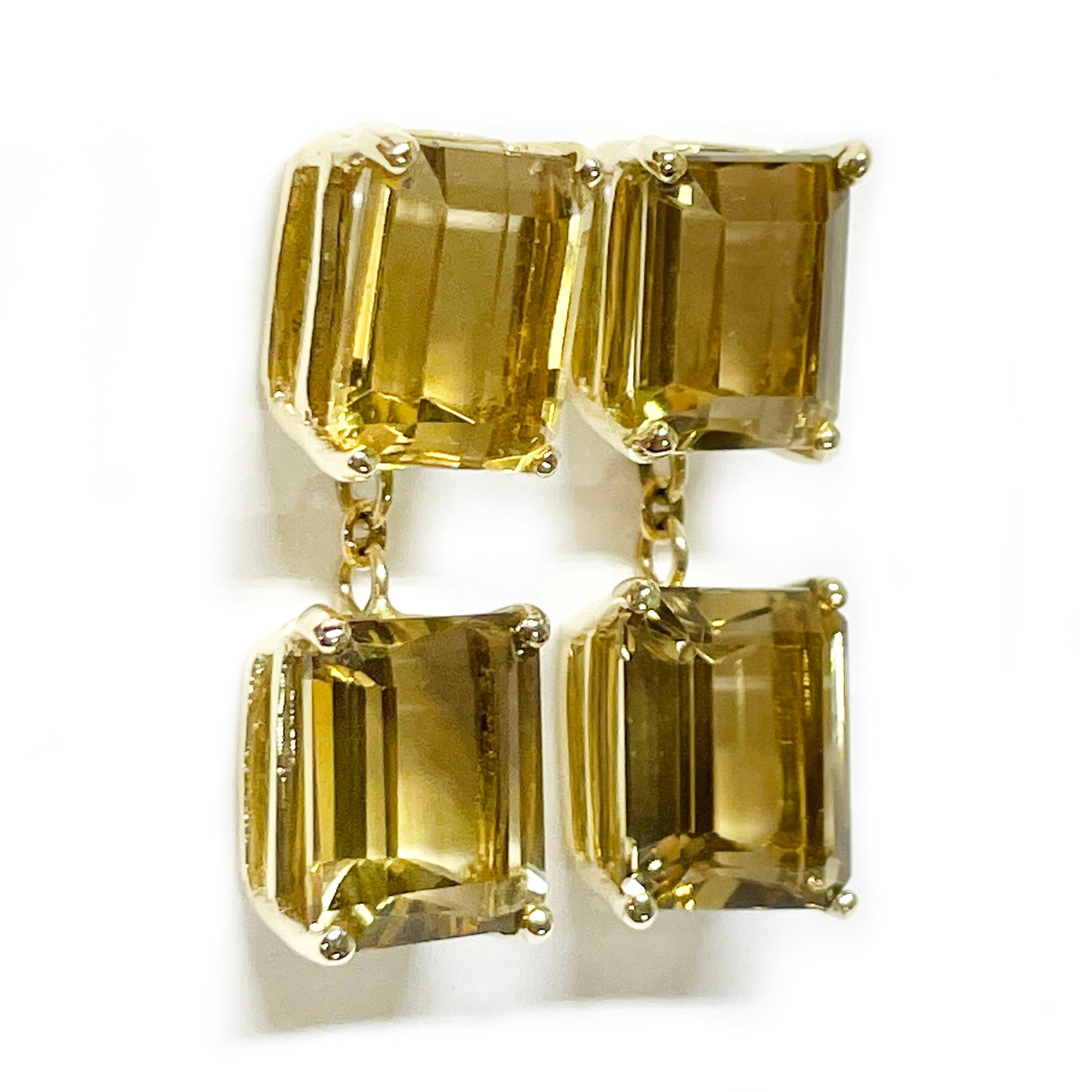 14 Karat Yellow Gold Citrine Dangle Earrings. The earrings each feature a two 9 x 7mm Citrine emerald-cut gemstones. The light gold/brown color gemstones are four-prong-set in a yellow gold basket settings. Their combined total carat weight is