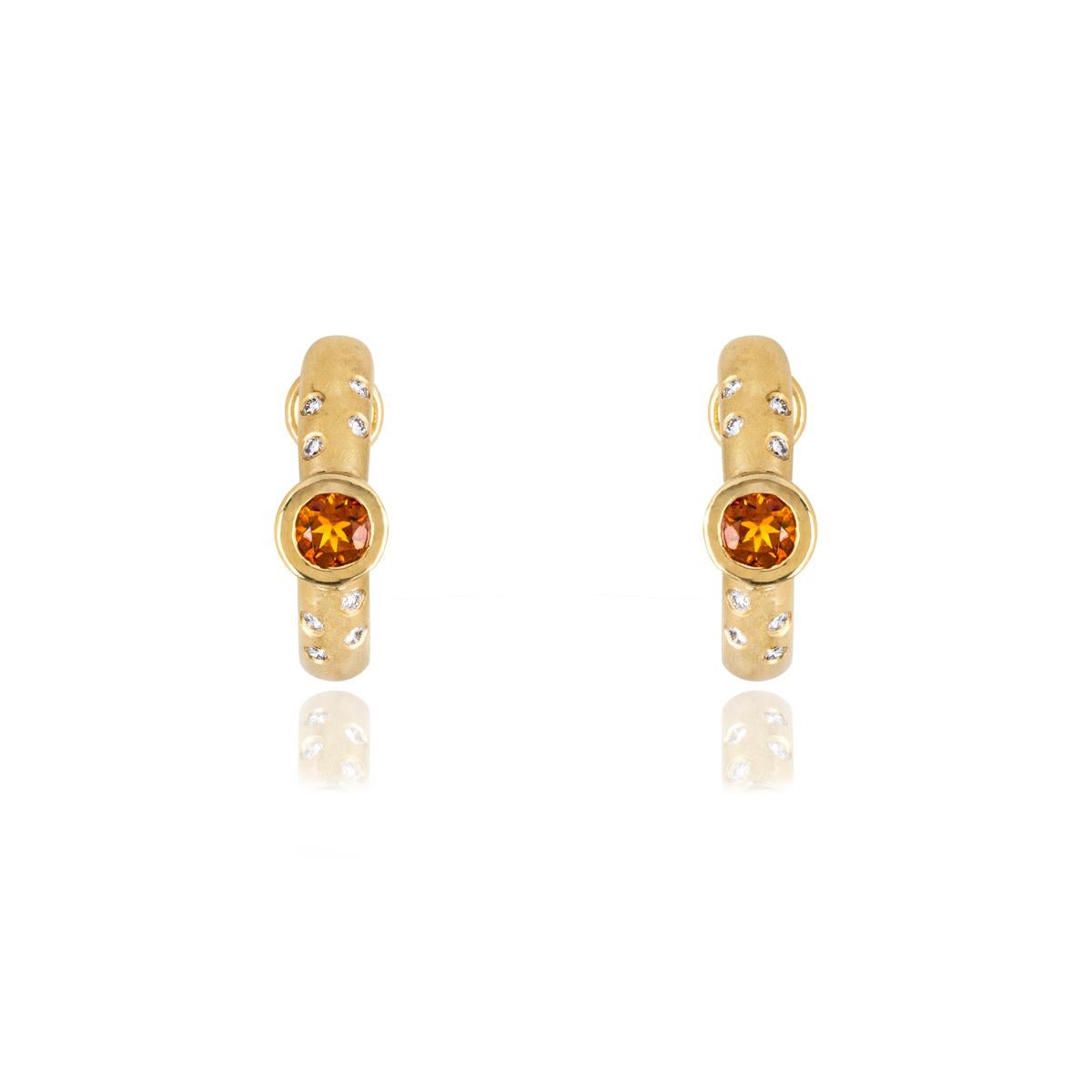 A modern pair of 18k yellow gold citrine and diamond earclips. Each half hoop is bezel set to the centre with a circular faceted citrine weighing approximately 0.44ct each. Complementing the citrine are 8 round brilliant cut diamonds set to each