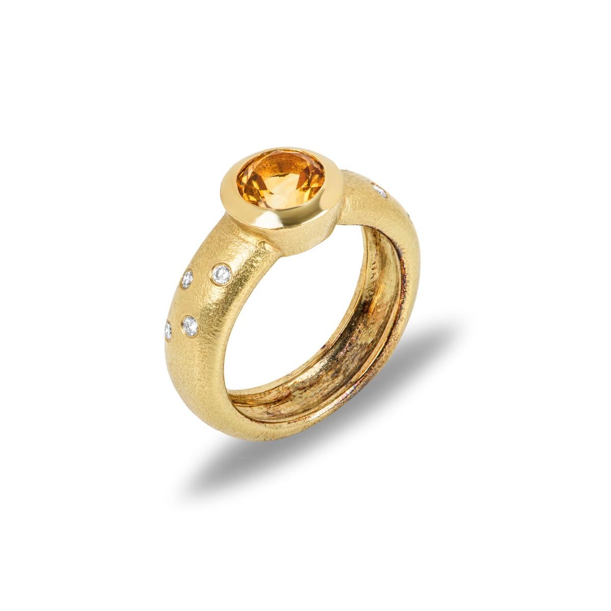 A modern 18k yellow gold citrine and diamond ring. The ring is set to the centre with a round cut citrine in a rubover setting, weighing approximately 1.15ct. Further complementing the citrine are 4 diamonds set to either side with an approximate