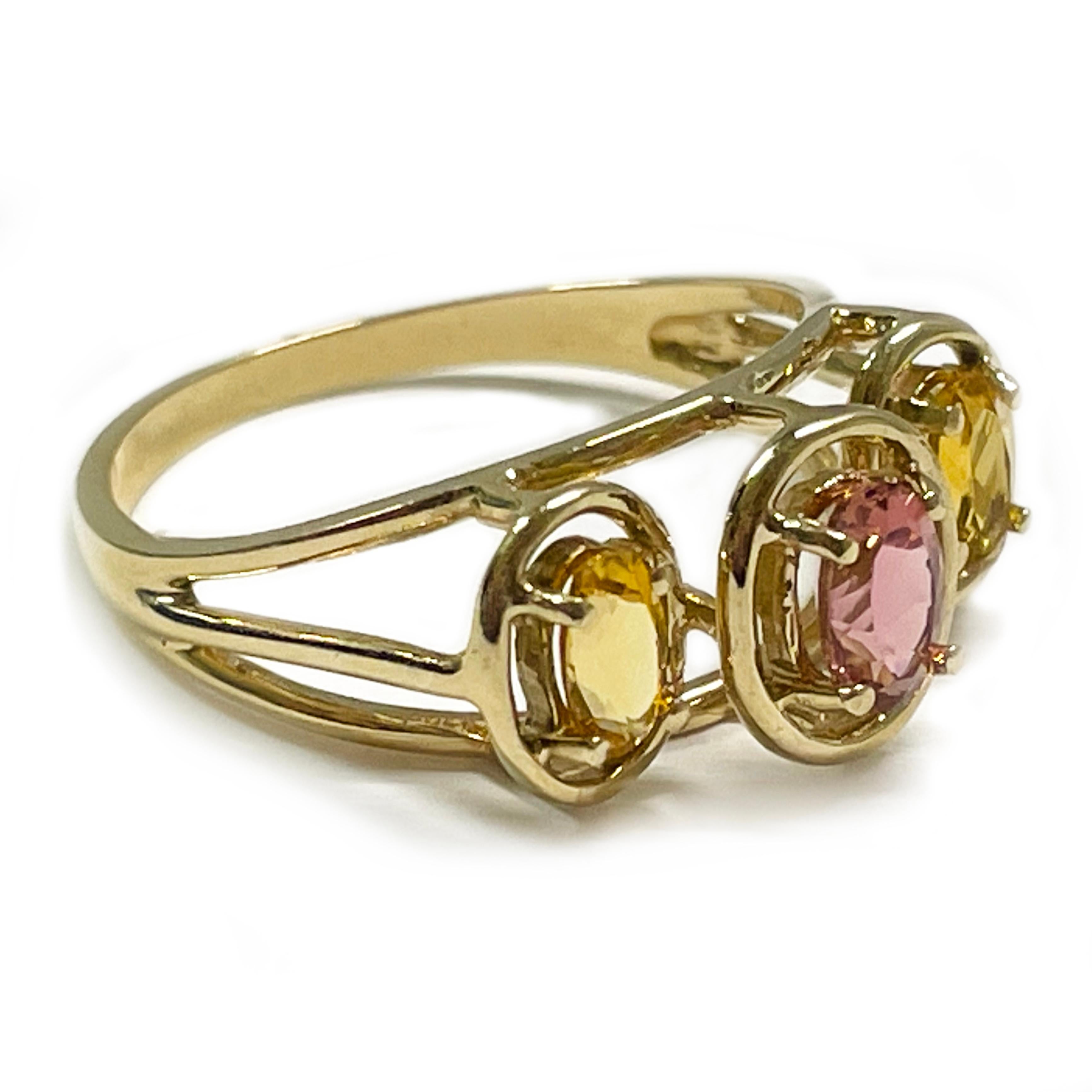 10 Karat Yellow Gold Citrine Rhodolite Three-Stone Ring. The ring features three oval open bezels with a split band. Set in the middle top bezel is an oval Rhodolite light pink in color and measuring 5.9 x 3.9mm. The other side stones are a light