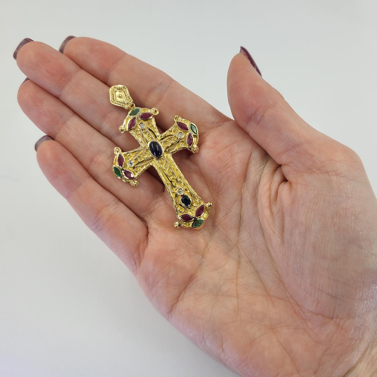 18 Karat Yellow Gold Gemstone Cross Pendant Featuring 8 Marquise Rubies, 4 Round Diamonds, 4 Marquise Emeralds, & 2 Sapphires Totaling Approximately 1.00 Carat. Textured Design with Contrasting Finish. 2.5 Inches Long. Finished Weight Is 10.0 Grams.