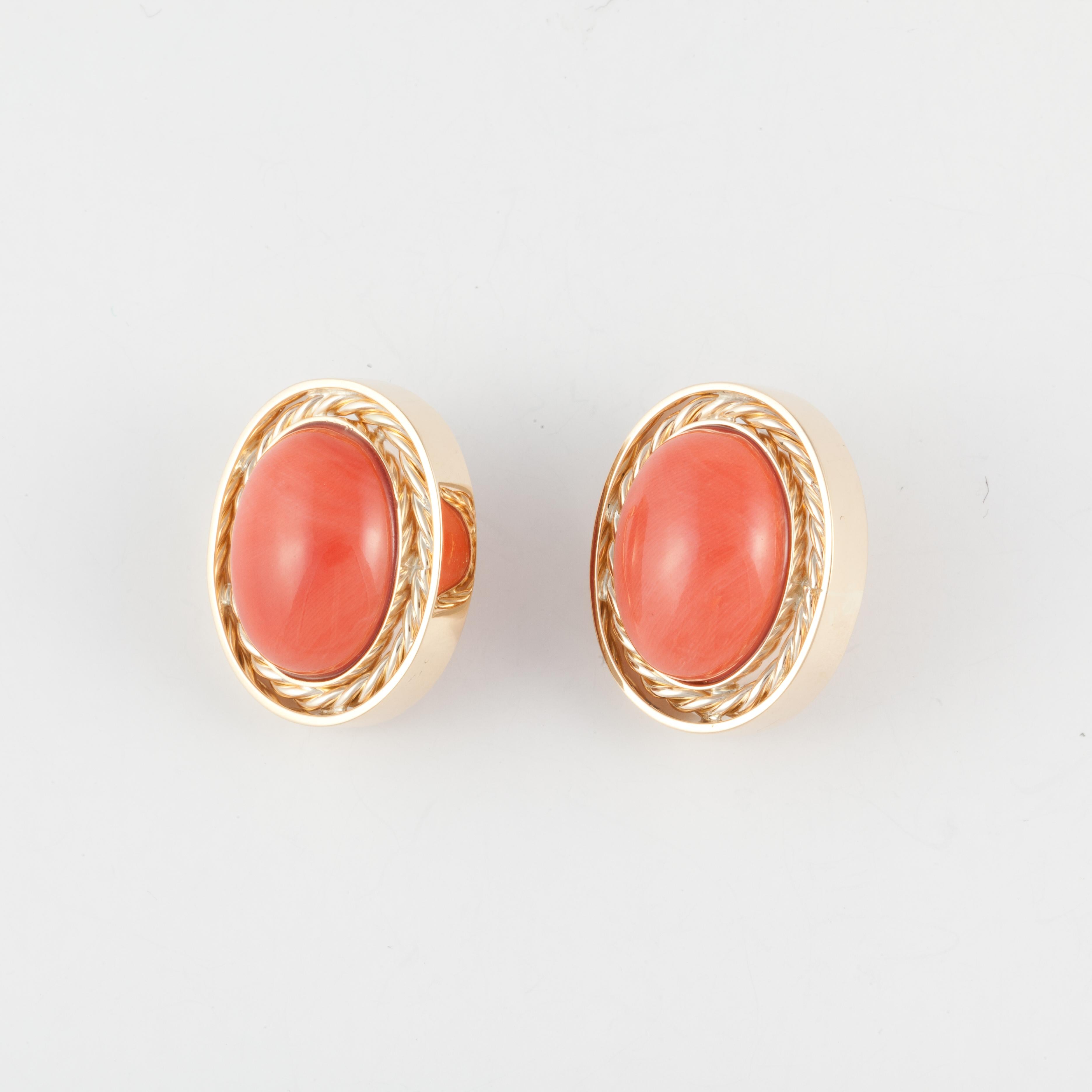 14K yellow gold earrings featuring an oval shaped coral stone framed by a rope design.  They measure 1 1/8 inches long by 7/8 inches wide and are a clip style.  