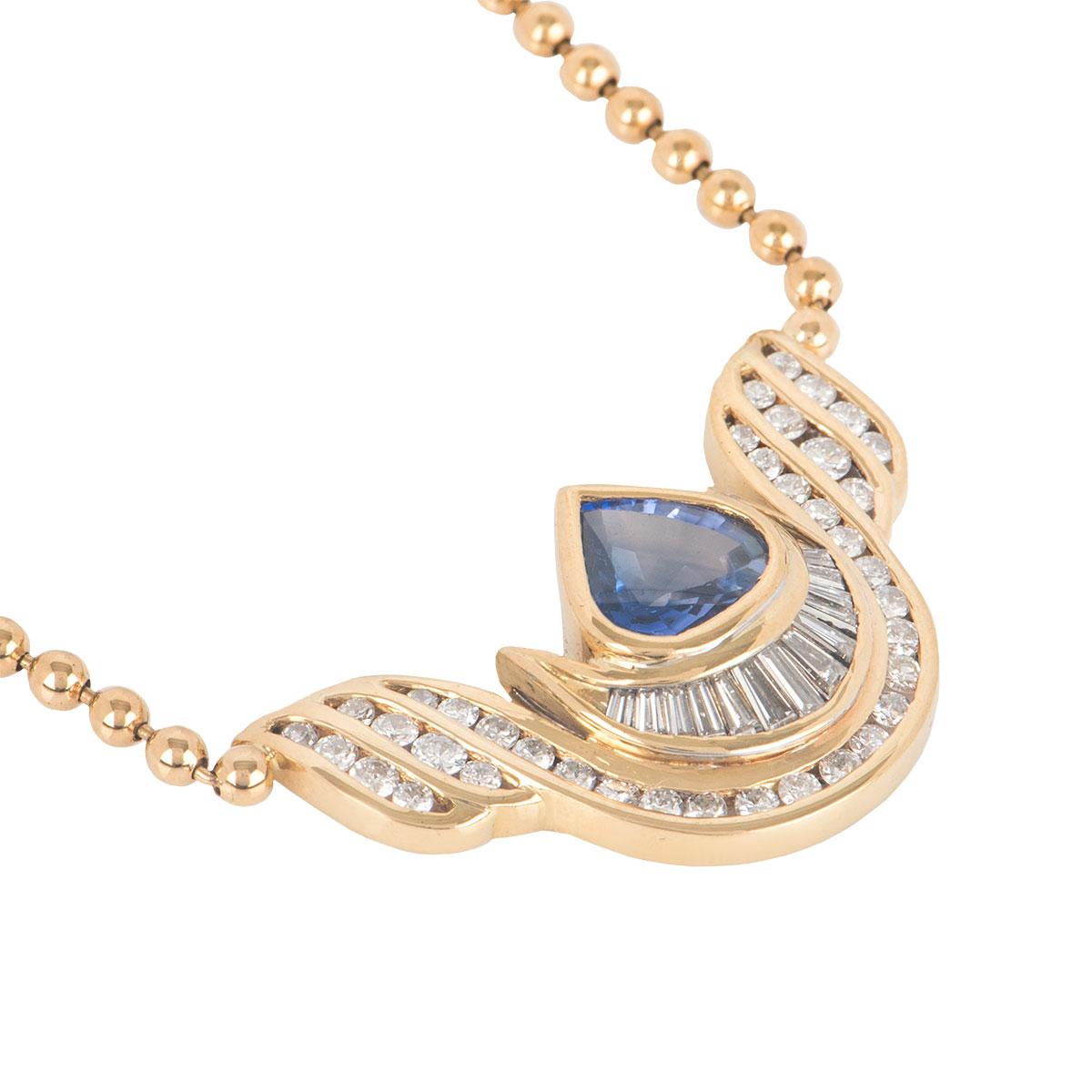 An 18k yellow gold diamond and topaz necklace. The necklace features a pear shaped topaz set to the centre with a row of tapered baguette cut diamonds and 3 rows of channel set round brilliant cut diamonds around it in a wing design. The topaz