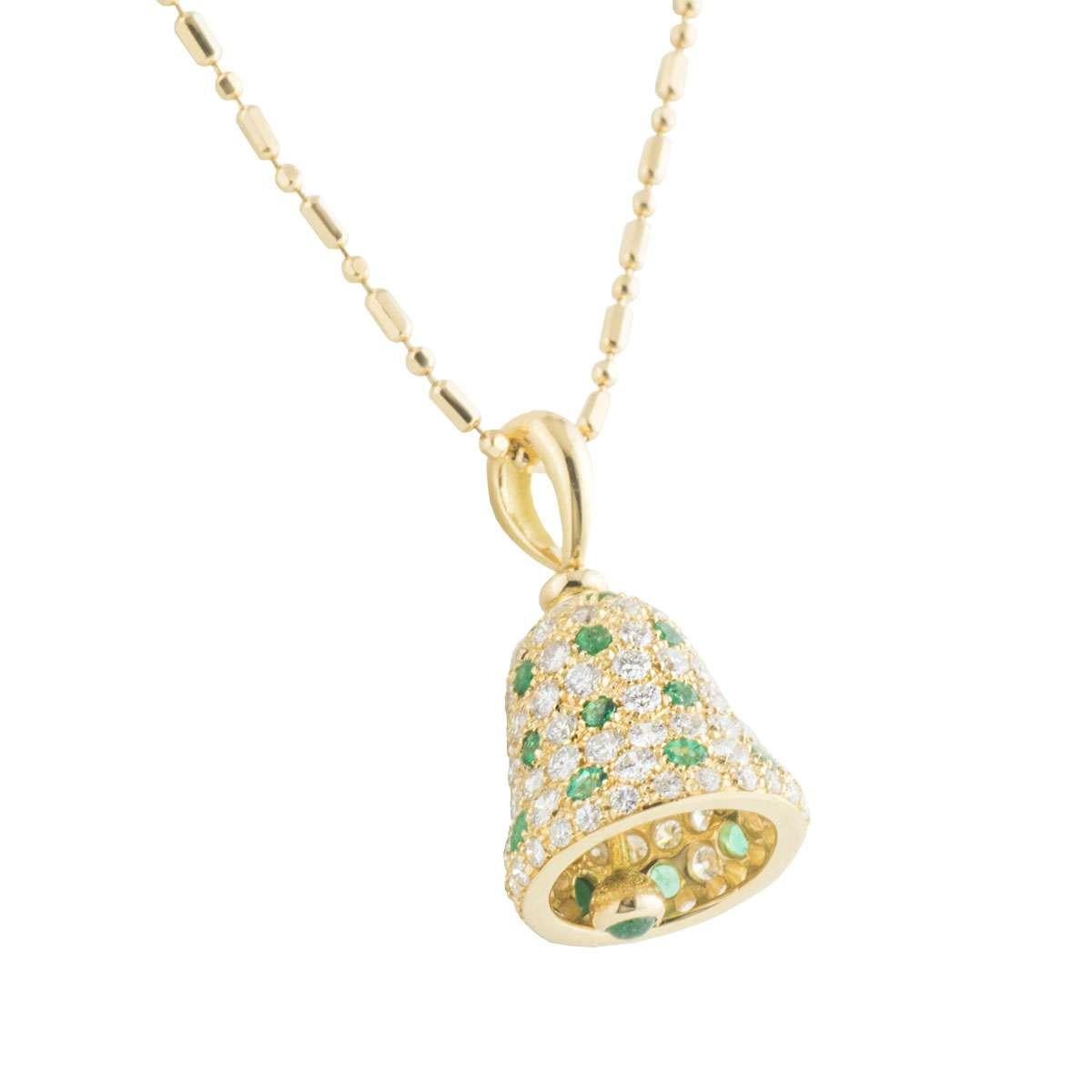 A beautiful 18k yellow gold diamond and emerald bell pendant. The pendant comprises of a bell motif encrusted with round brilliant cut diamonds alternating with round brilliant cut emeralds. The pendant has a gold bar dangling freely through the