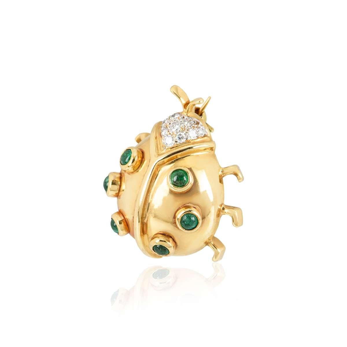 An 18k yellow gold Ladybird brooch. The brooch is set with 6 cabochon emeralds throughout the body and 10 round brilliant cut diamonds set in the head. The emeralds total approximately 0.30ct and the diamonds total approximately 0.12ct. The