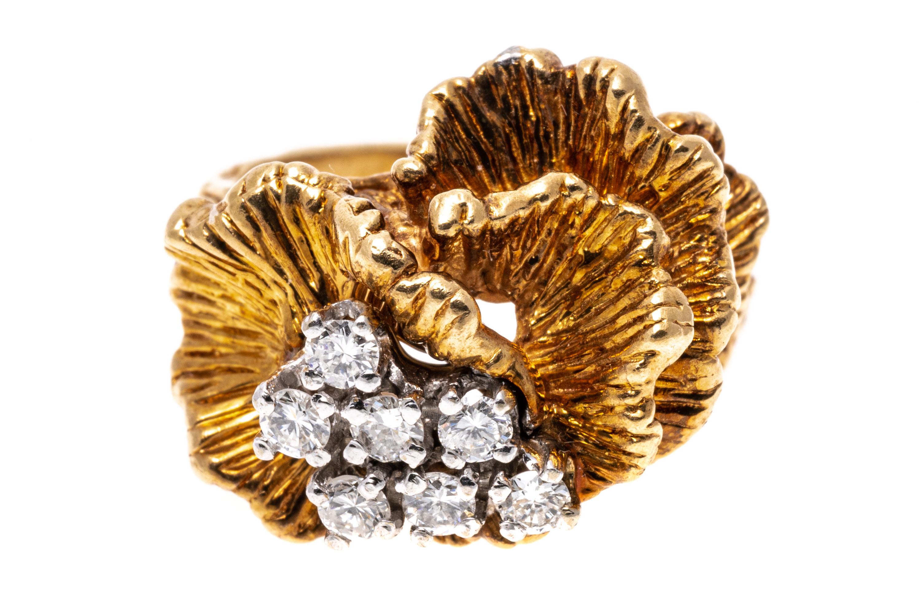 14k yellow gold ring. This beautiful and unusual ring is a chased cockscomb form, decorated with a cluster of round brilliant cut diamonds, approximately 0.23 TCW, prong set. The ring is finished by split shoulders and a double shank, patterned in a