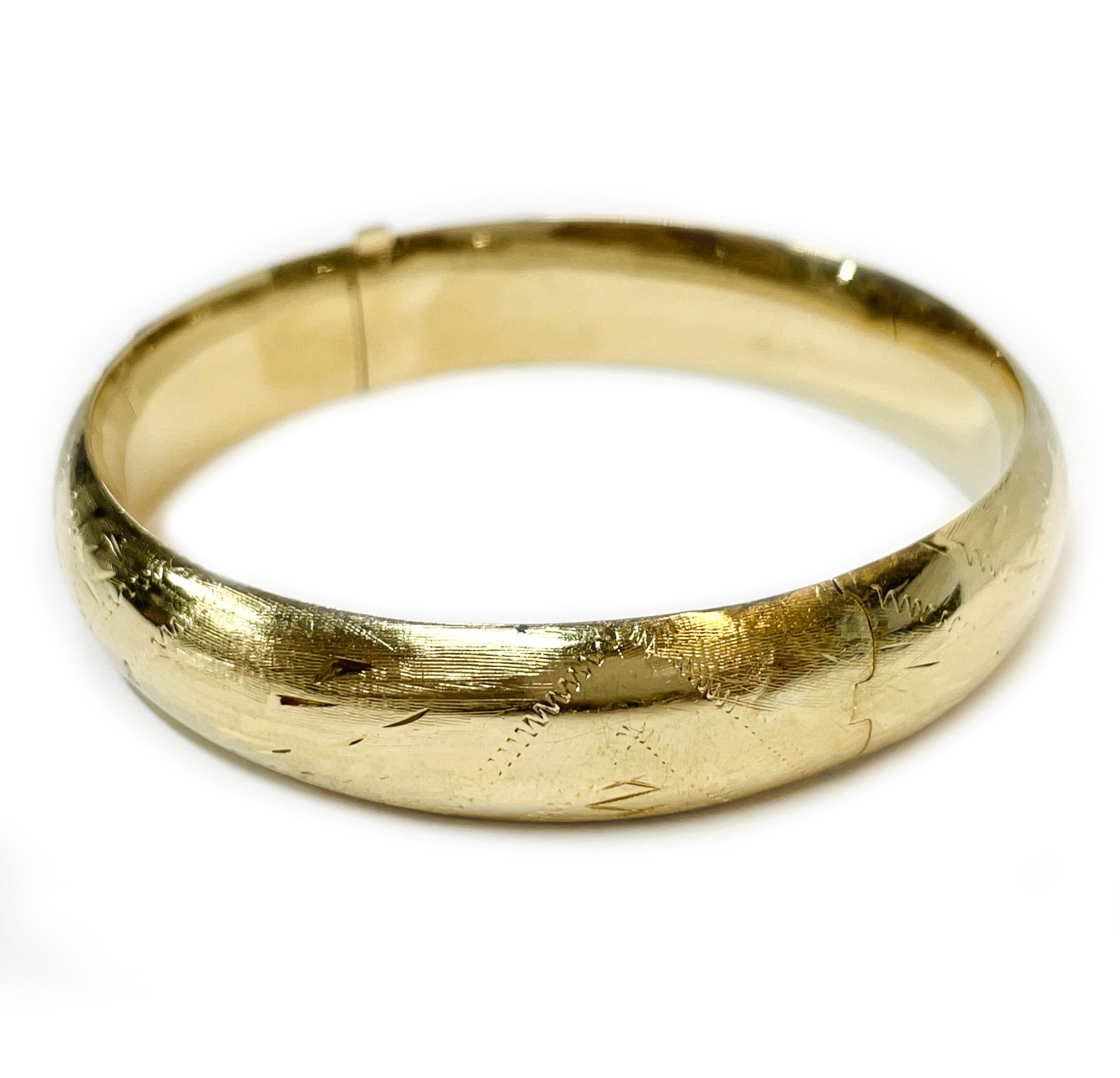 14 Karat Yellow Gold Diamond-Cut Bangle Bracelet. The hollow bracelet has diamond-cut accents and leaf and zig-zag designs with a textured and smooth finish. Stamped on the hinge of the bangle is 14K. The bracelet is 13.0mm wide. The bangle diameter