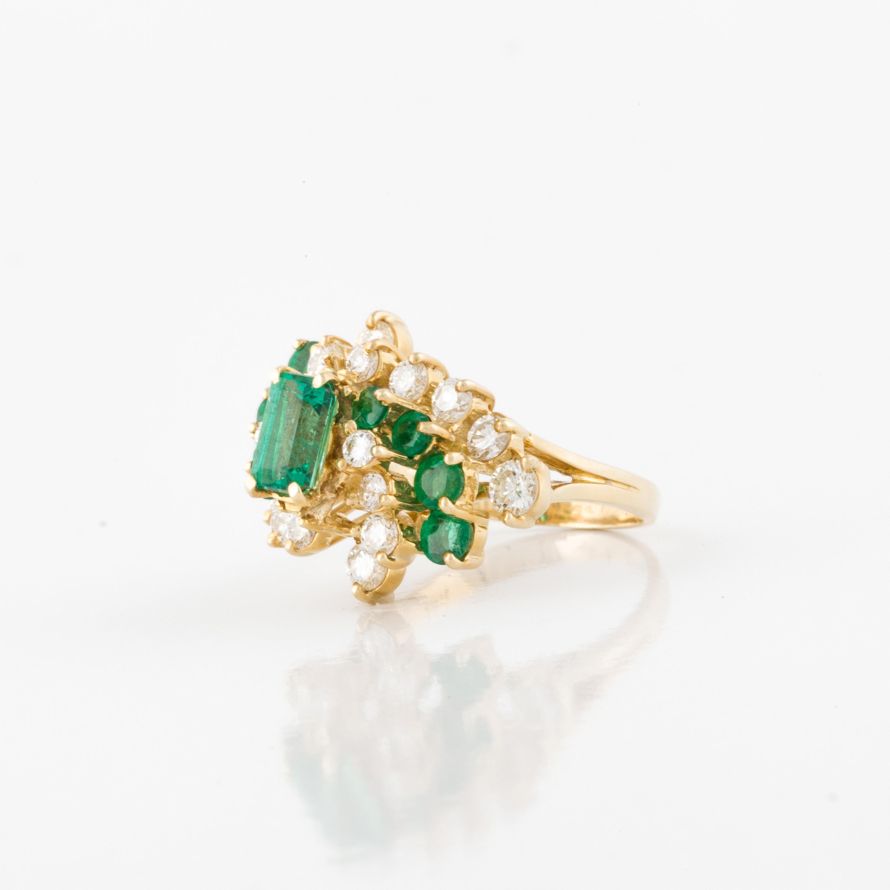 18K yellow gold diamond and emerald ring in a waterfall style.  The ring features one emerald-cut emerald and eight round emeralds accented by eighteen round diamonds totaling 1.25 carats; G-H color and VVS-VS clarity. The ring is currently a size