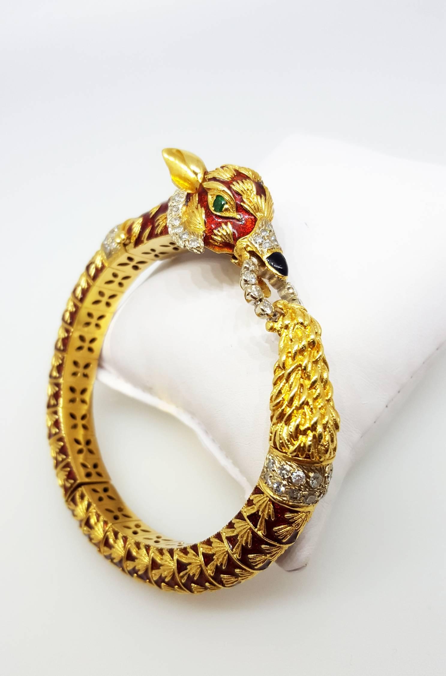 An 18 karat yellow gold fox bracelet. The bracelet is set with 58 diamonds that weigh 1.45cttw. The bracelet features a, red enamel, fox head design with emerald eyes. The bracelet has a double push button release. 