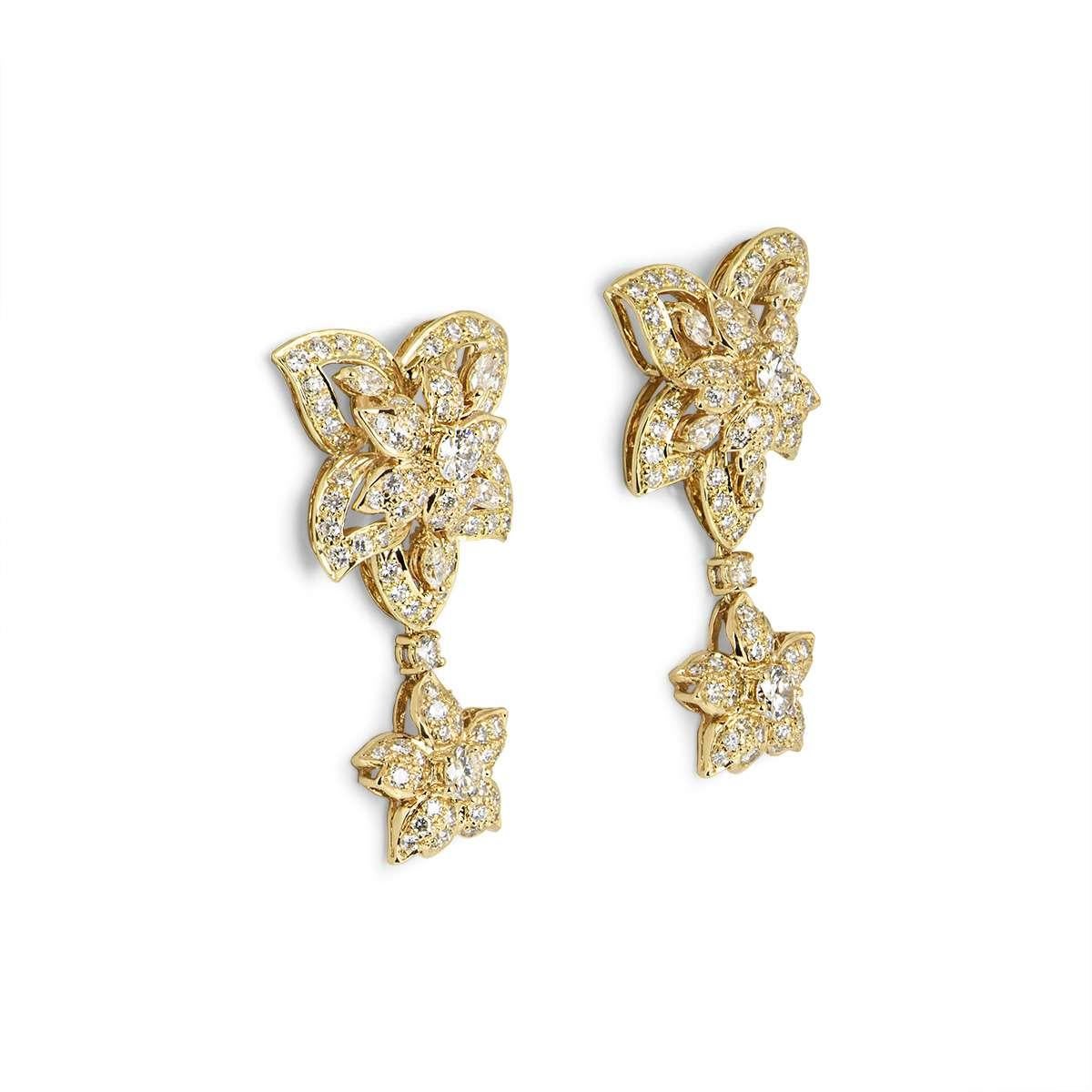 A pair of 18k yellow gold diamond set flower earrings. The earrings each feature a large openwork flower suspending a smaller flower motif. The earrings are set with round brilliant cut and marquise cut diamonds with a total weight of approximately