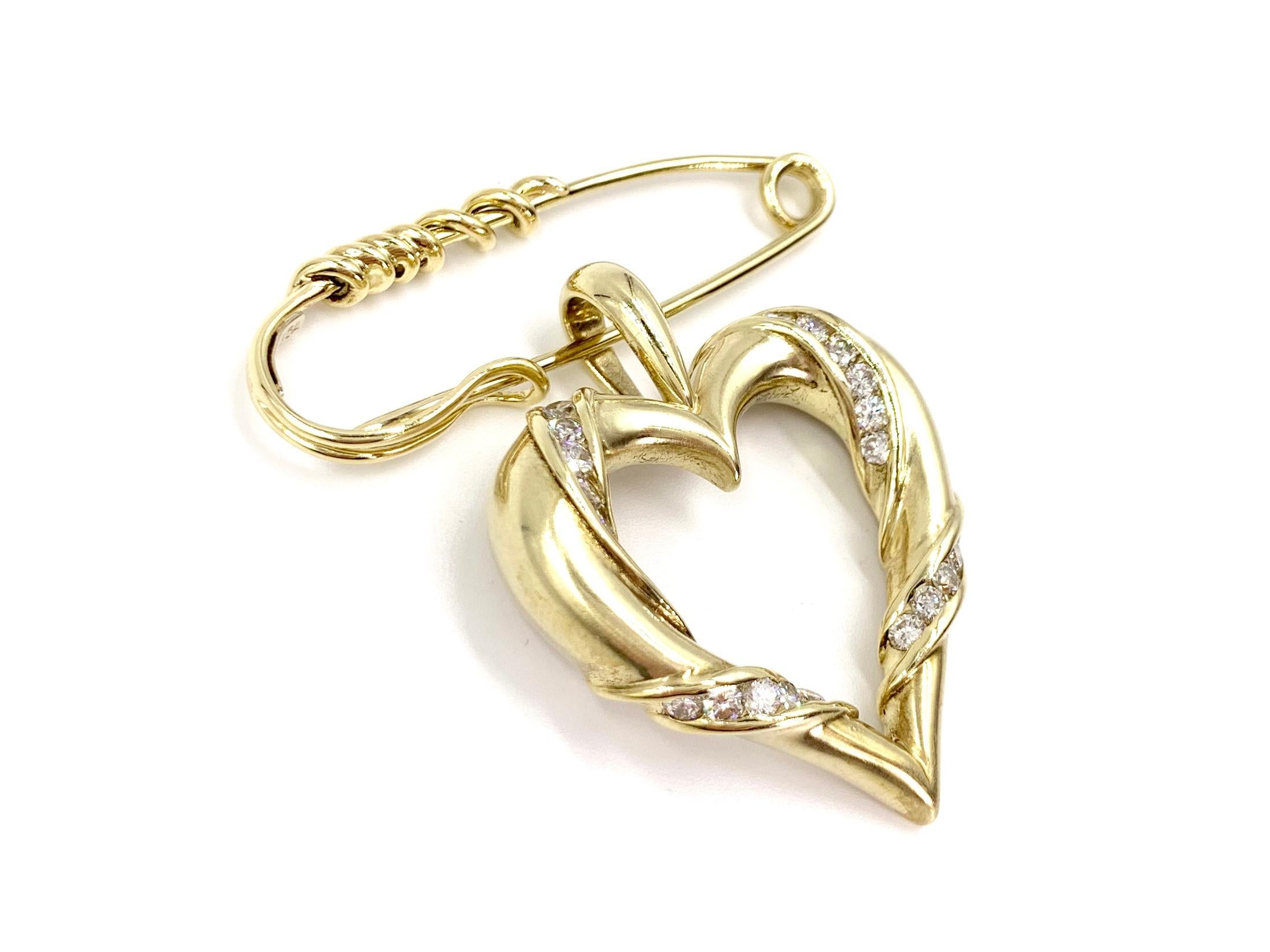 Made with superior quality by expert jeweler, Jose Hess. This satin finished 14 karat yellow gold open heart dangles beautifully from a polished yellow gold safety-pin style brooch. High quality channel set round brilliant diamonds have a total