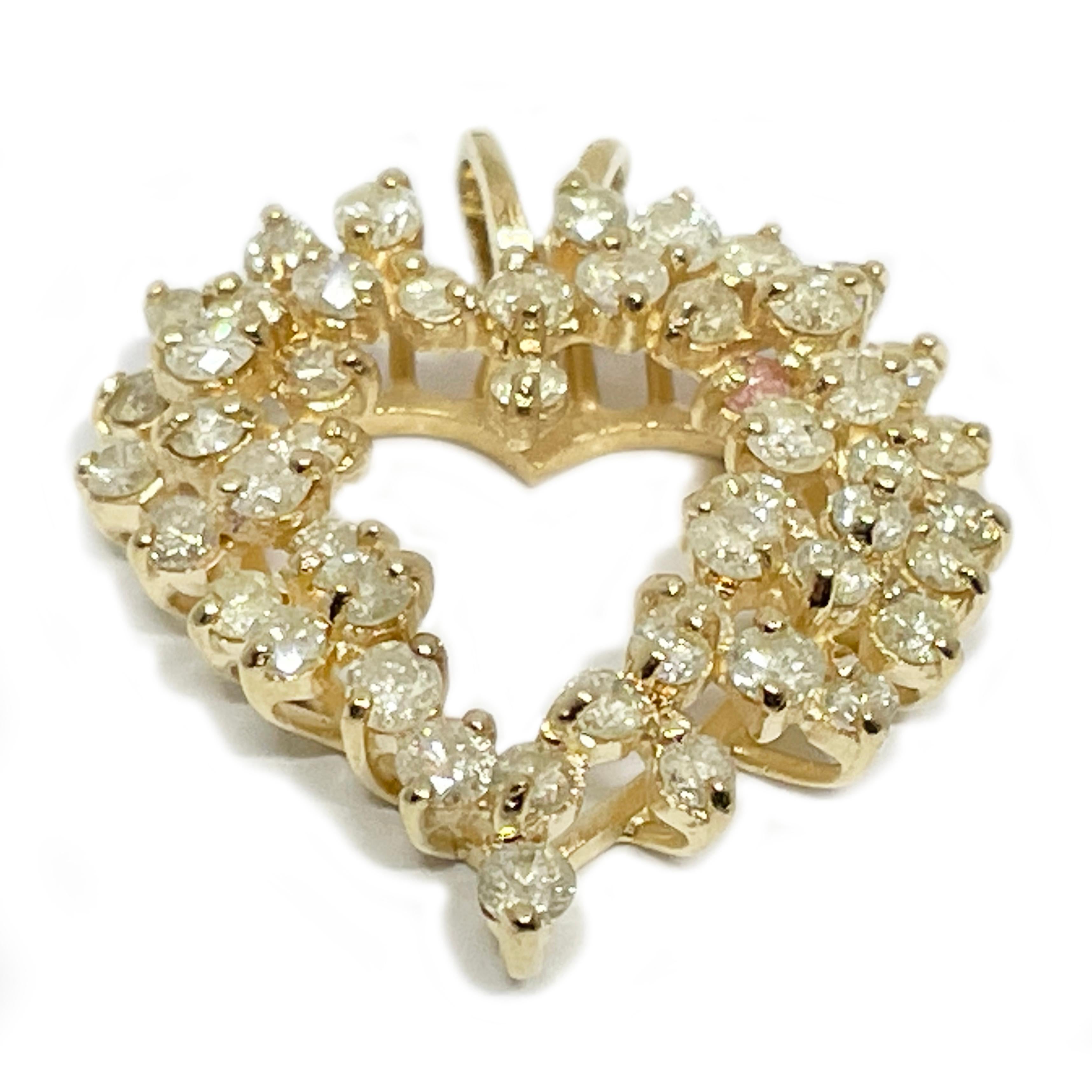 14 Karat Yellow Gold Diamond Heart Pendant. The pendant has an orgnaic heart-shape design with forty-nine white diamonds and one pink diamond. The pendant has an attached rabbit bail. The diamonds vary in size and have an approximate carat total