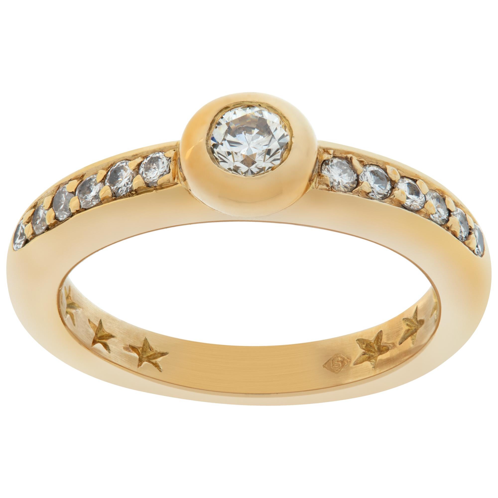 Yellow gold diamond ring with center bezel set diamond with side diamond accents For Sale