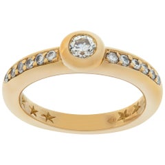 Yellow gold diamond ring with center bezel set diamond with side diamond accents