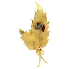 Spilla in oro giallo con diamanti e rubini e smalto a foglia strutturata con testa di gallo