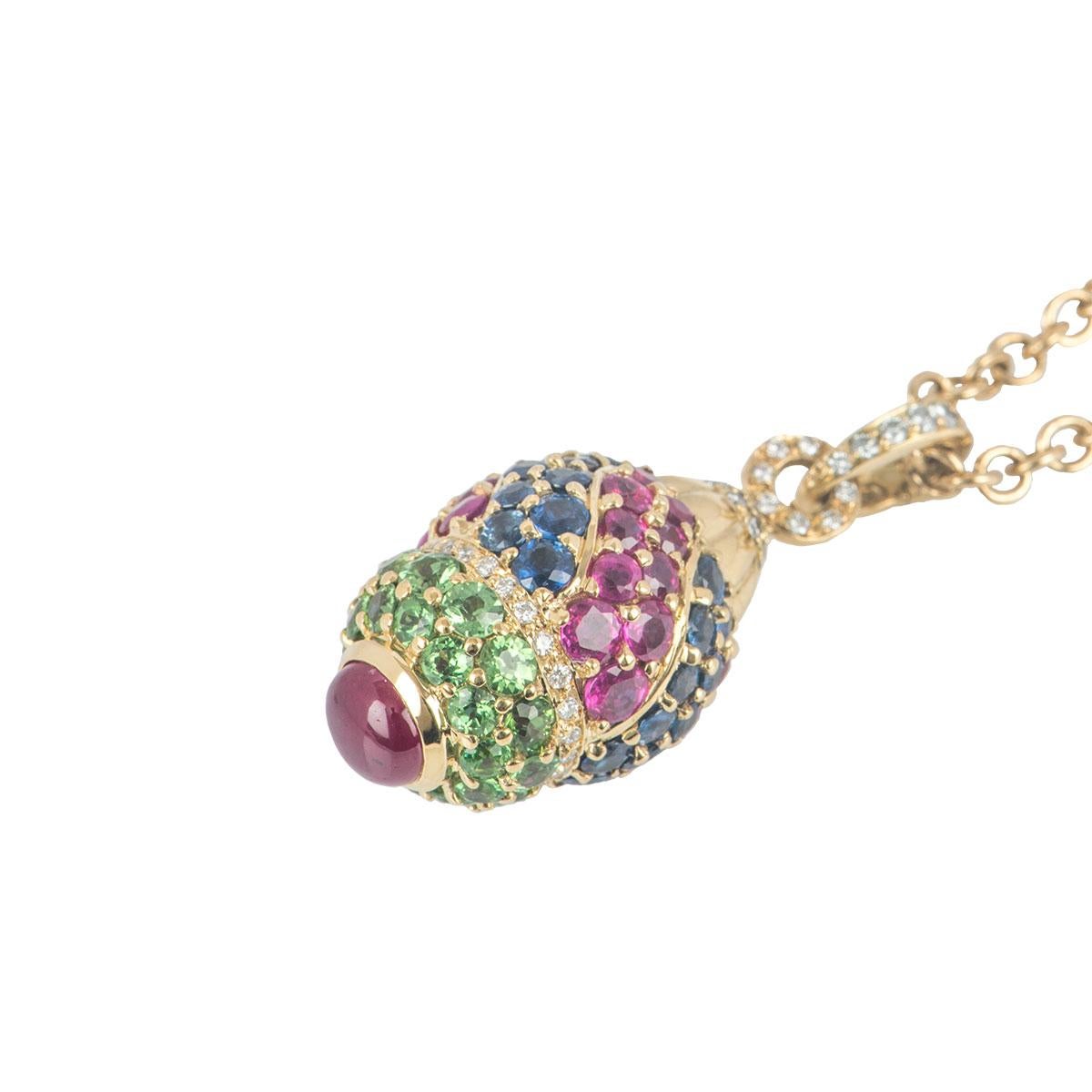An 18k yellow gold diamond and multi gem egg pendant. The pendant features round brilliant cut diamonds in a pave setting on the bail, head and middle of the pendant. The chain of the pendant contains 6 sapphires evenly spaced apart, with sapphires