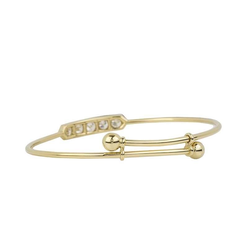 An 18k yellow gold diamond set children's bangle. The bangle is set to the centre with 5 round brilliant cut diamonds each set in a four claw setting with a total weight of approximately 0.85ct, F/G colour and VS in clarity. The bangle expands to