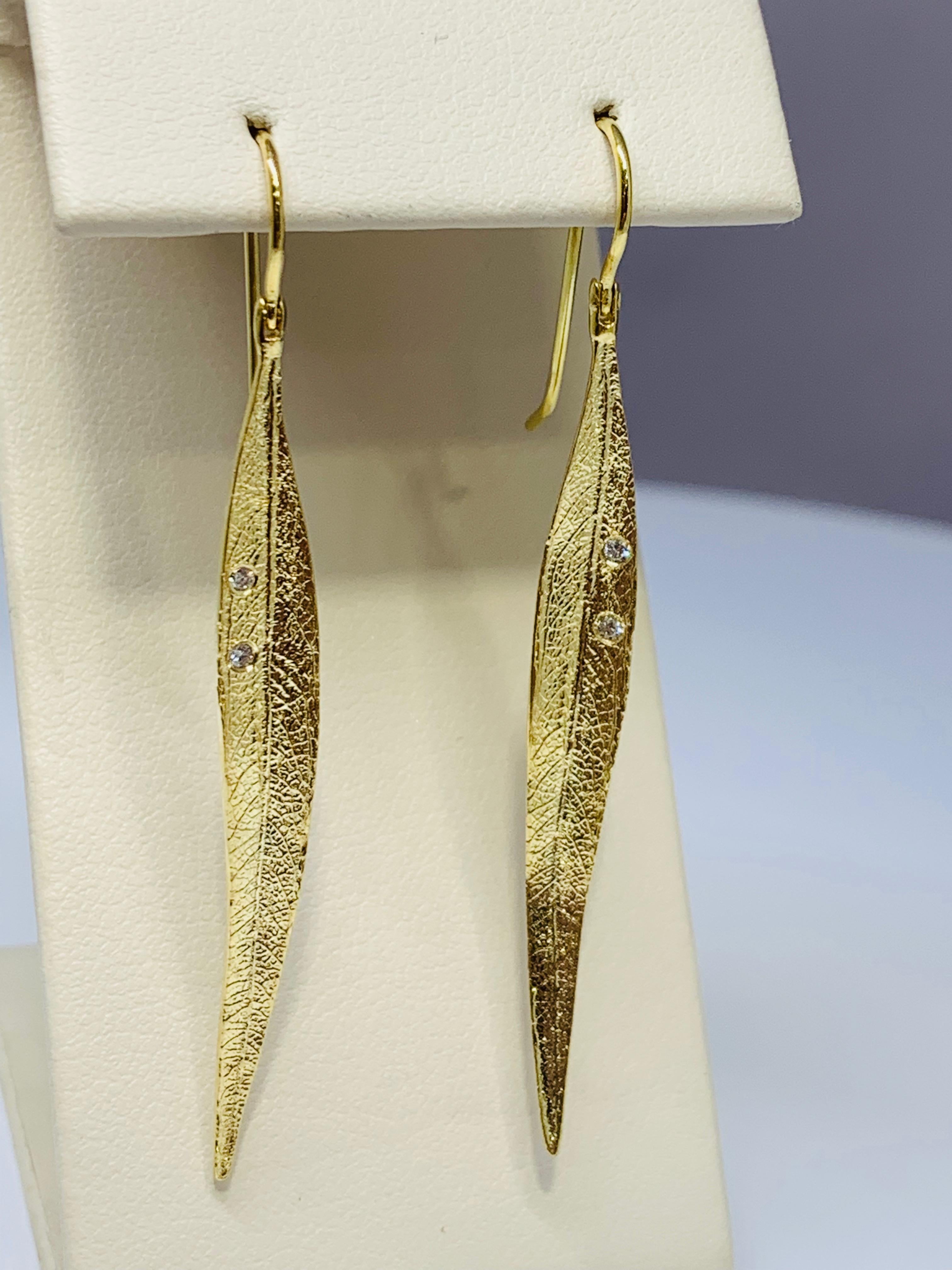 These gorgeous Cherie Dori earrings feature 0.04 carats of round diamonds, holding two small diamonds on each leaf. The earrings are textured for a natural leaf-like effect. These earrings are made of 18K yellow gold and are approximately 2 inches