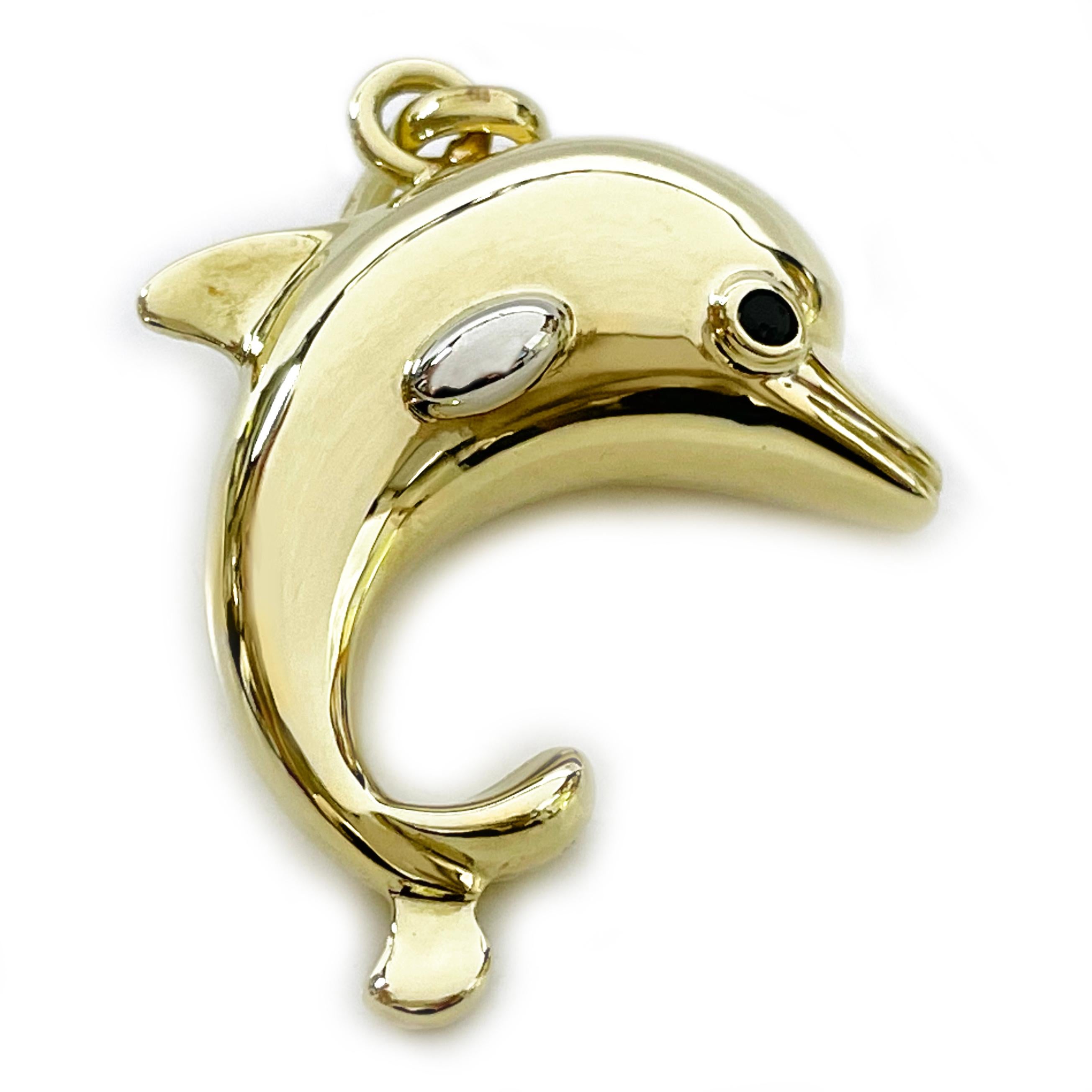 Yellow and White Gold Dolphin Pendant. The pendant features a three-dimensional yellow gold dolphin with black faceted stones bezel-set in the eyes. The side fins are in white gold while the rest of the pendant is yellow gold, the pendant has an