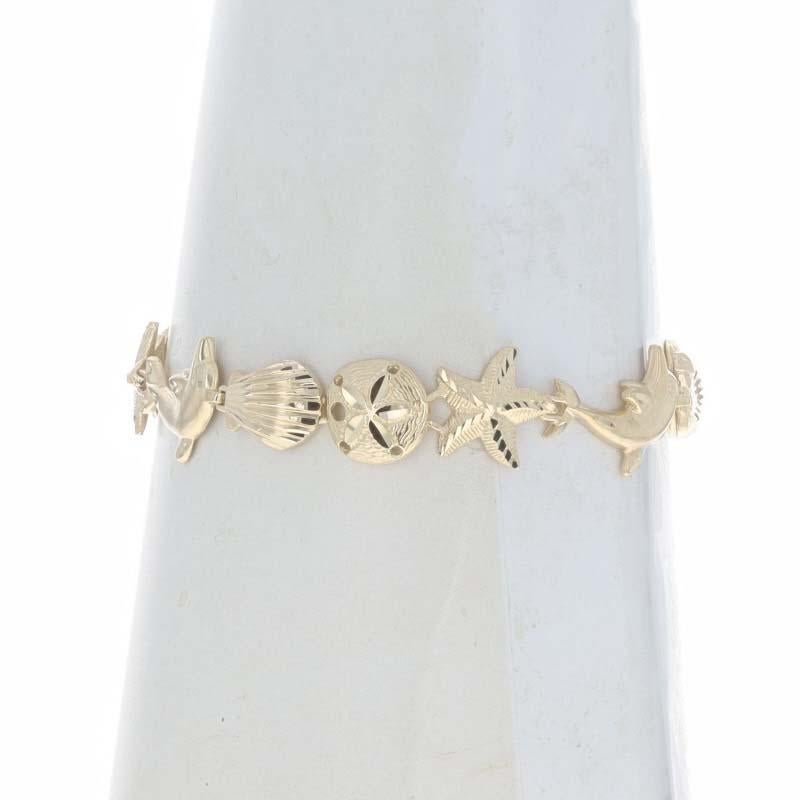 Metal Content: 14k Yellow Gold

Style: Link
Fastening Type: Lobster Claw Clasp
Theme: Dolphin Seashell Sand Dollar Starfish, Ocean Life
Features: Matte & Smooth Finishes with Etched Detailing

Measurements

Adjustable length: 7