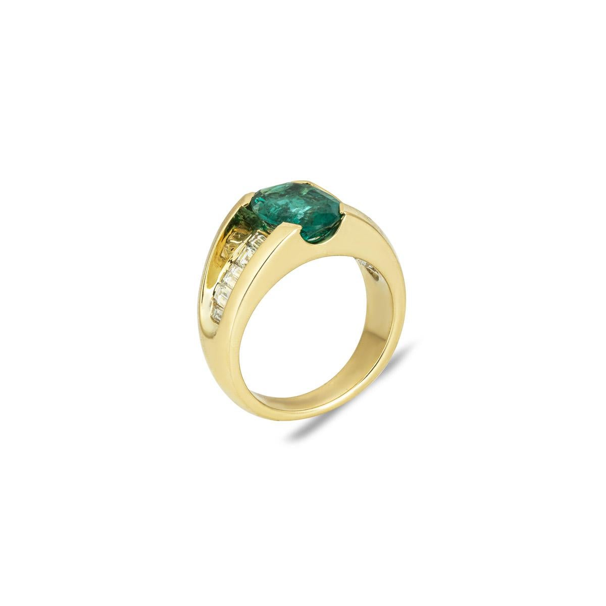 A striking 18k yellow gold emerald and diamond dress ring. The ring showcases an oval cut emerald with a weight of 2.25ct and displays a medium green hue. Further accentuating the emerald are 10 baguette cut diamonds graduating in size on the