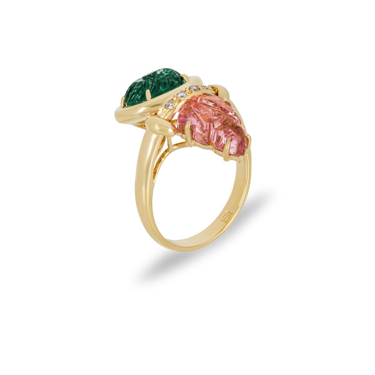 An intricate 18k yellow gold multi-gemstone and diamond ring. The dress ring consists of an oval cut carved emerald displaying a dark green hue, a floral cut pink tourmaline displaying a peachy-pink hue and 4 diamonds. The 4 round brilliant cut