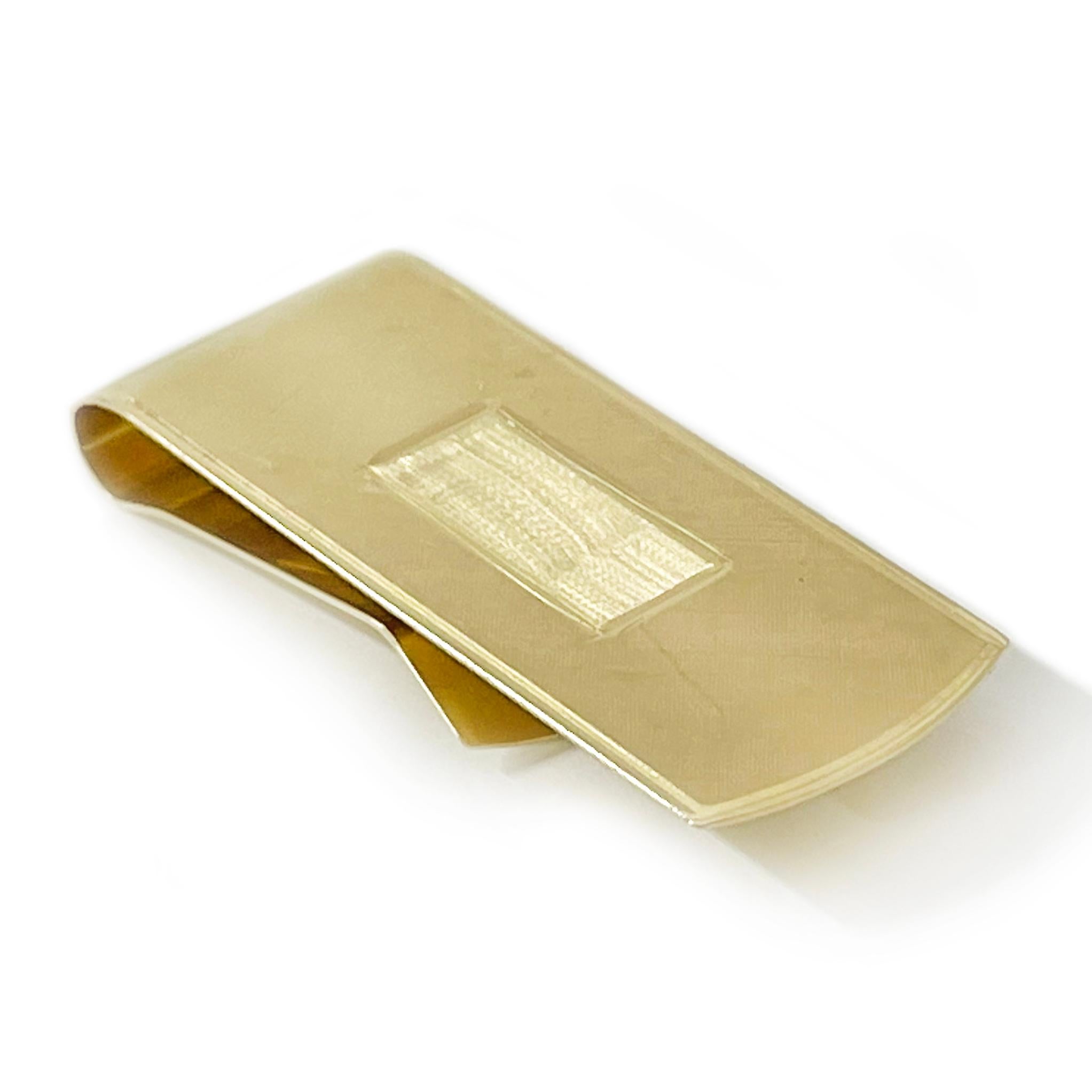 14 Karat Yellow Gold Engravable Money Clip. The money clip has a Florentine finish on the top and a smooth shiny finish on the back. The money clip measures 2.1