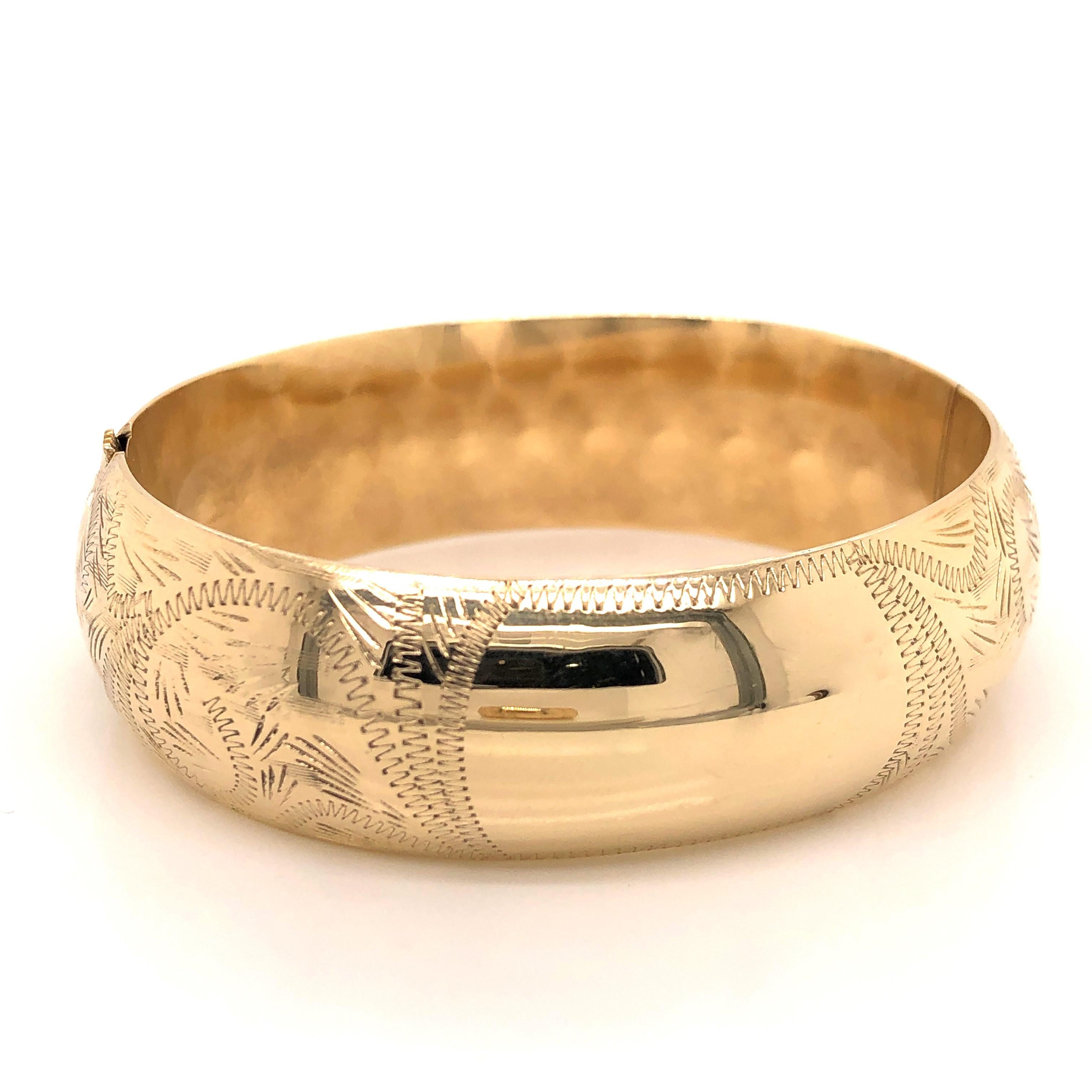In bright polished fourteen karat yellow gold, this beautifully hand engraved Antique bangle bracelet will be a constant in your jewelry wardrobe.
Measures 2-1/4 x 2 inches with a 6-1/2 inch radius.  At 3/4 inch in width, the attractive rounded face