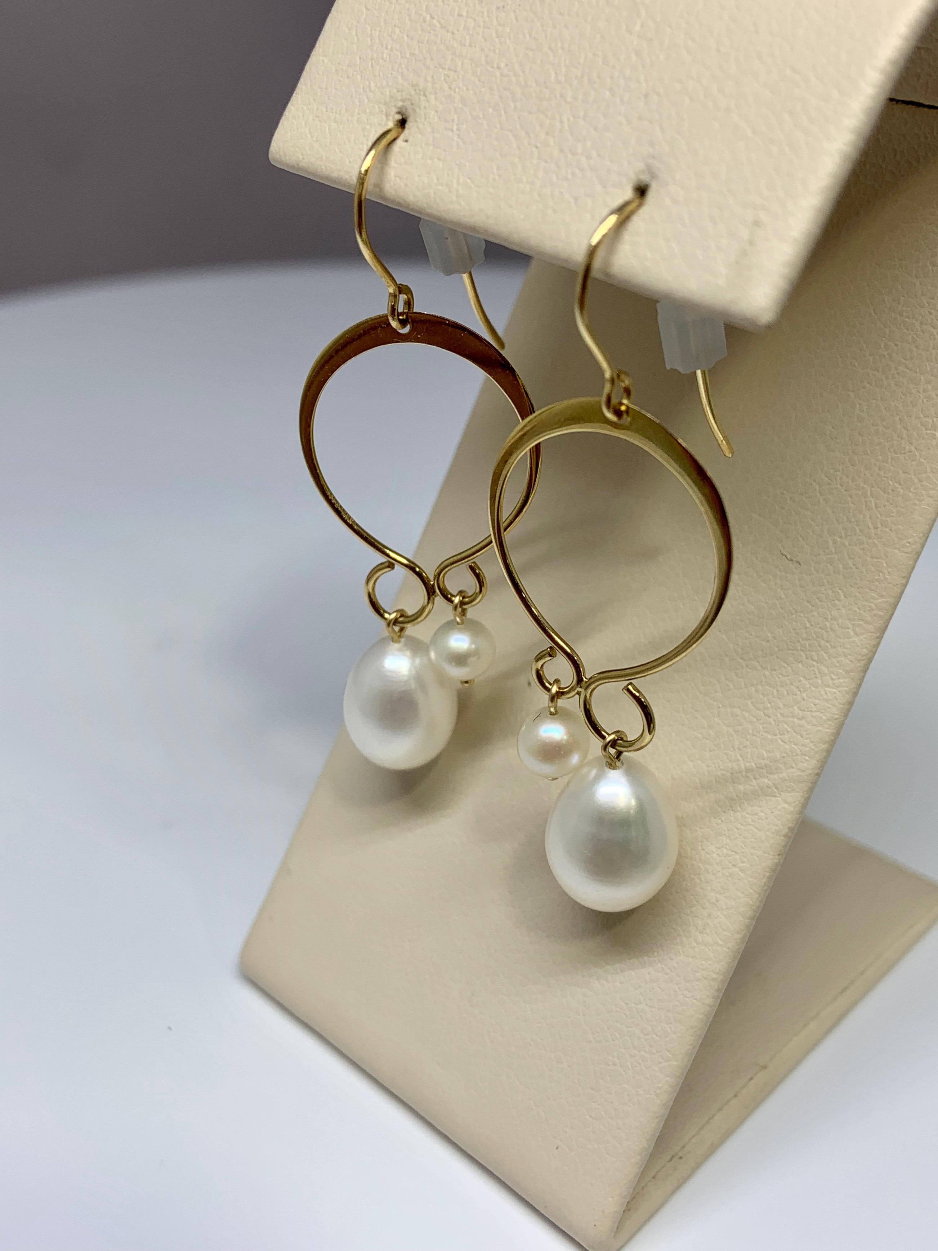 These gorgeous earrings include two beautiful staggered freshwater pearls per earring. The beautiful circular drop design gives these earrings an artsy appearance. These earrings are crafted out of 14K yellow gold. The largest pearls measure around