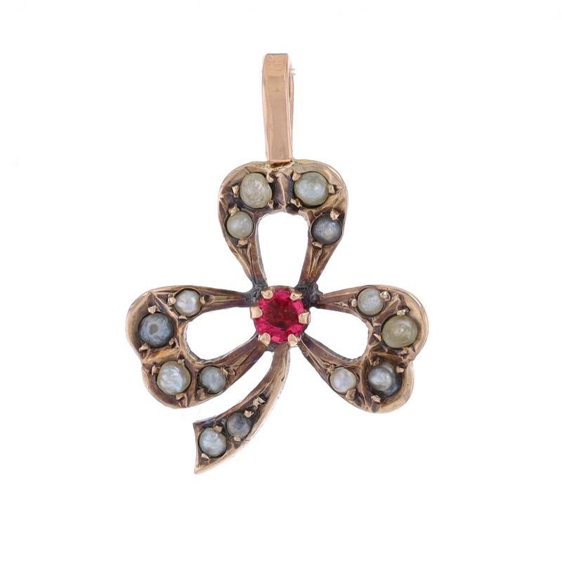 Era: Victorian

Metal Content: 9k Yellow Gold

Stone Information
Natural Garnet
Cut: Round
Color: Pinkish Red

Seed Pearls

Style: Solitaire with Accents
Theme: Three-Leaf Clover, Shamrock
Features: Open Cut Design

Measurements
Tall (from