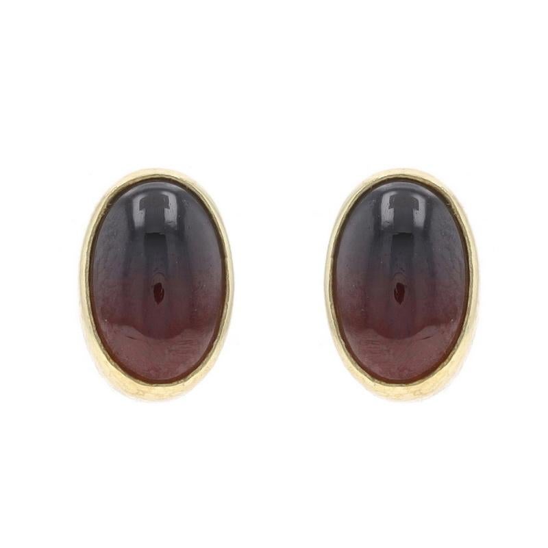 Metal Content: 14k Yellow Gold

Stone Information
Natural Garnets
Carat(s): 3.00ctw
Cut: Oval Cabochon
Color: Red

Total Carats: 3.00ctw

Style: Stud
Fastening Type: Pierced Screw-On Closures
Features: Bezel Set Stones

Measurements
Tall: 13/32
