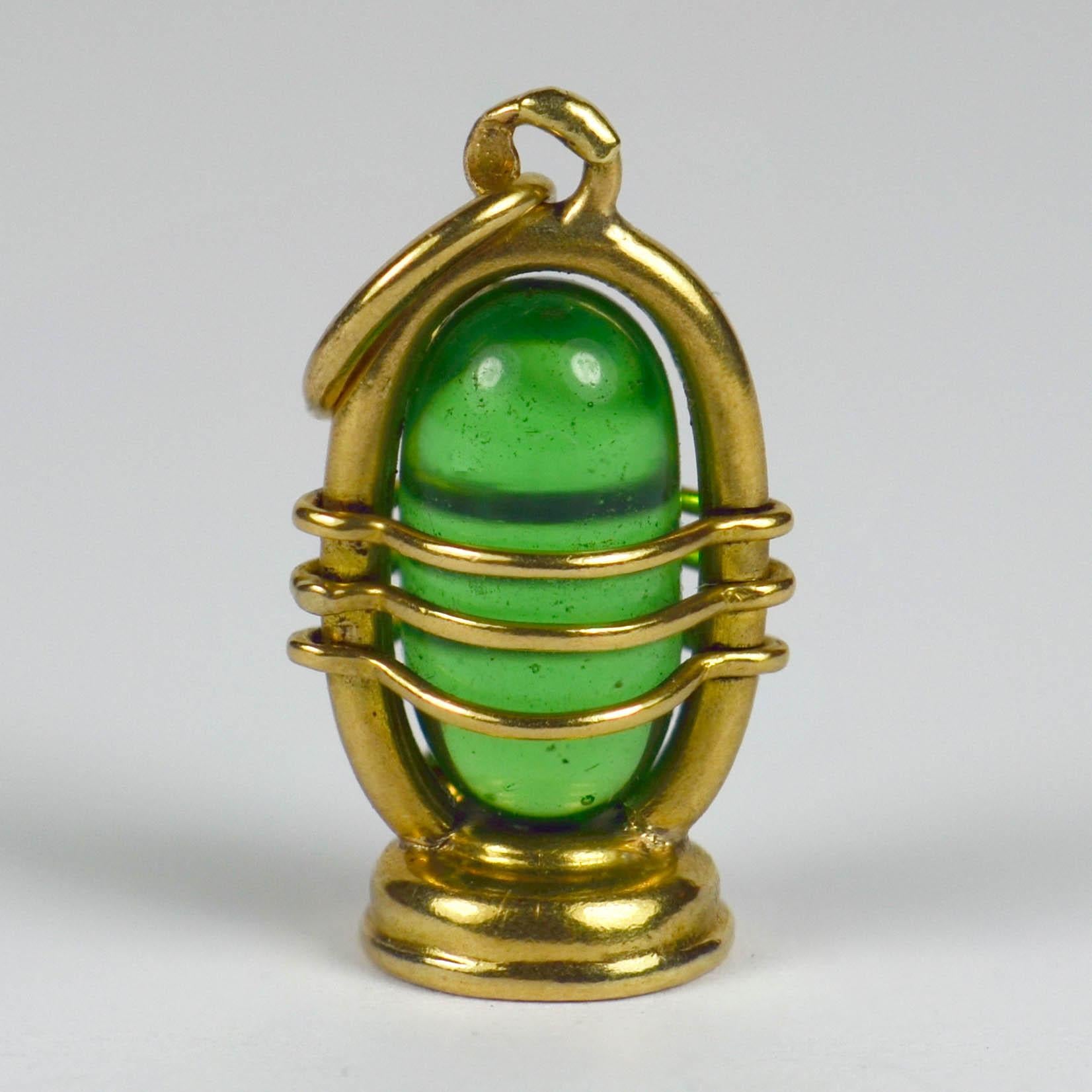 An 18 karat yellow gold charm pendant designed as an oil lantern with green glass insert. Stamped with the owl punch mark for French import of 18 karat gold.

Dimensions: 2 x 1 x 0.6 cm
Weight: 2.06 grams