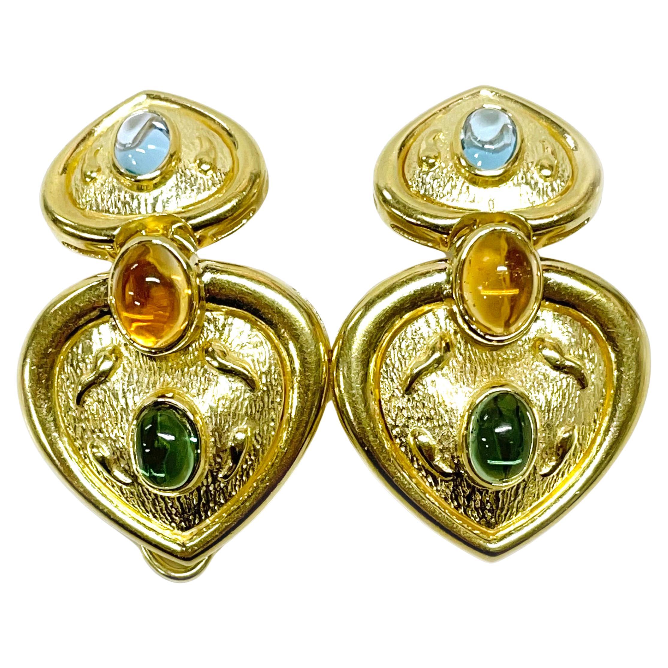 14 Karat Yellow Gold Heart Cabochon Earrings. These striking earrings make a statement with their bold heart design accented with colored gemstones. The earrings feature bezel-set oval cabochons of Blue Topaz, Citrine, and Green Tourmaline. The Blue