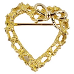 Broche en or jaune soulignant le contour d'un cœur avec un nœud
