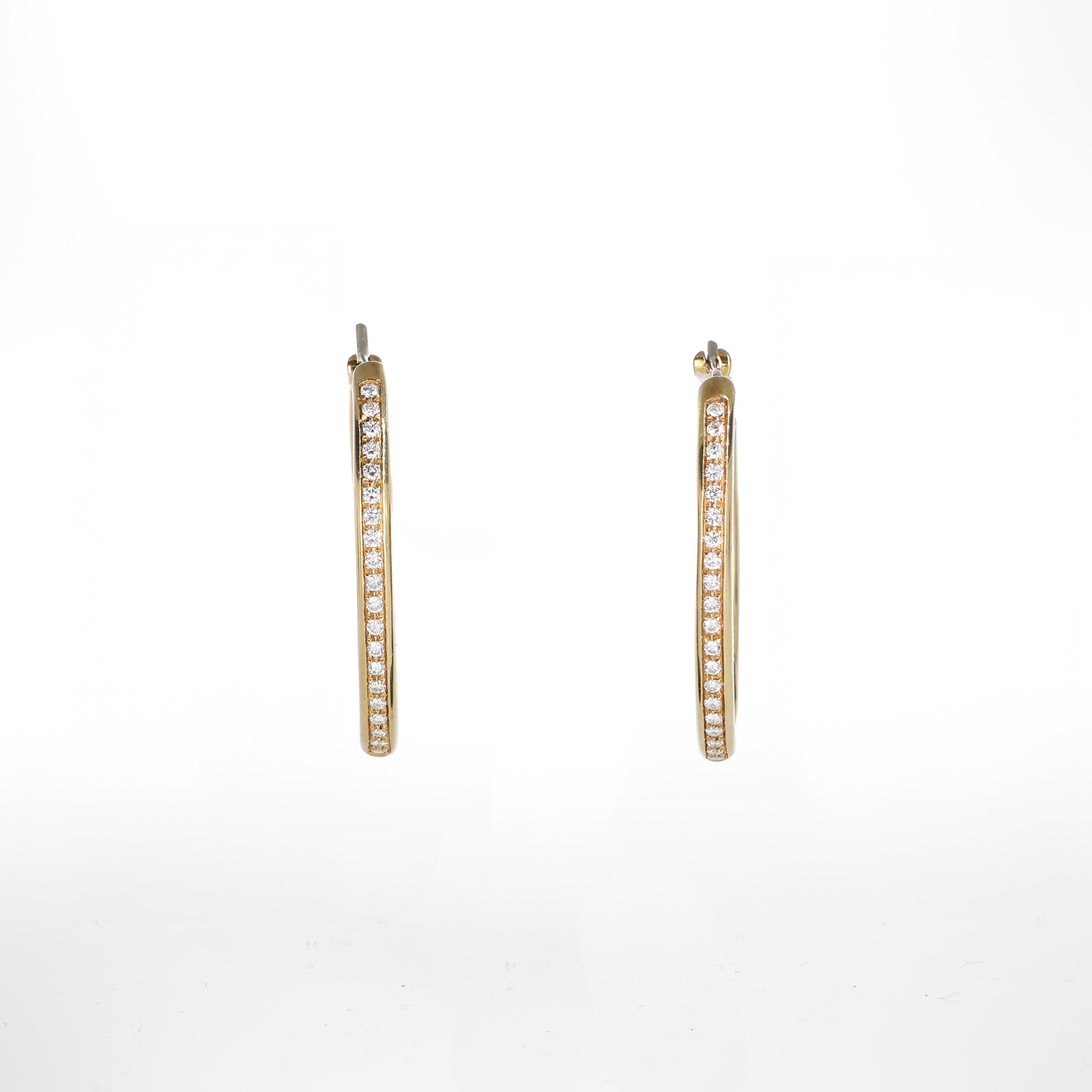 A timeless pair of hoop earrings crafted in yellow gold, featuring a central line of brilliant-cut diamonds totaling 0.74 carats. With their sleek and elegant design, these earrings offer a touch of understated glamour, perfect for any occasion.