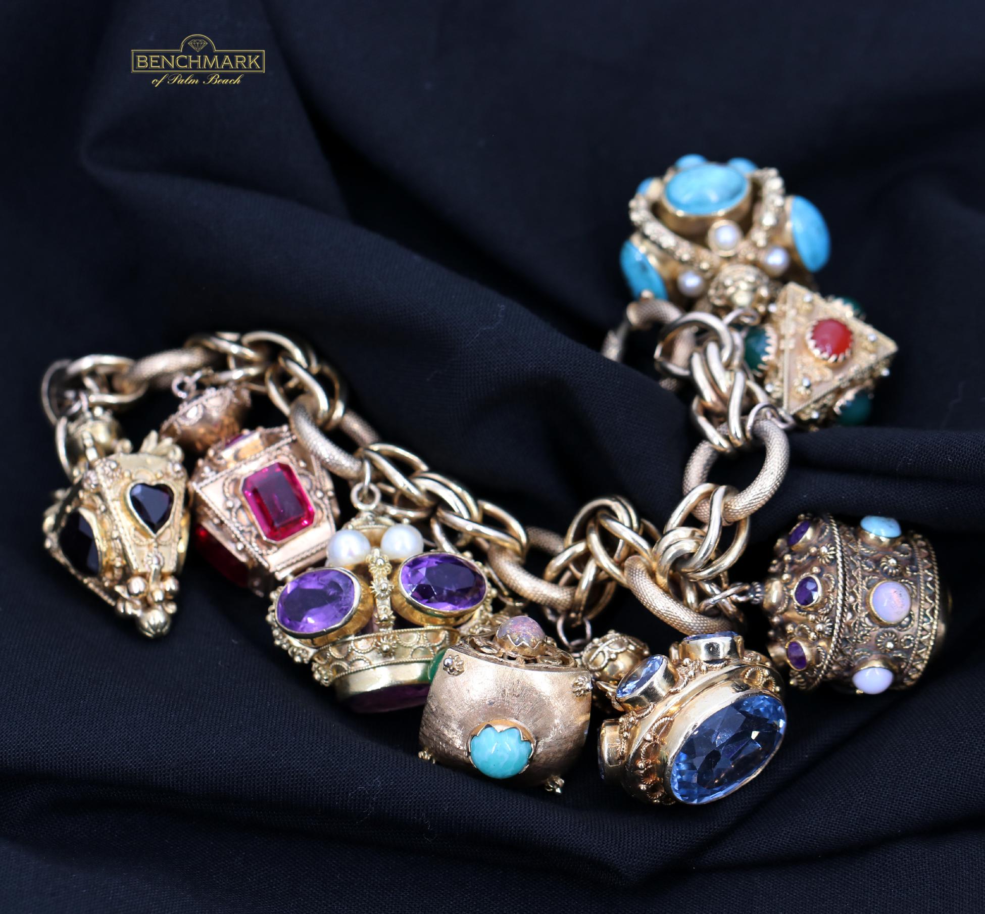 An 18K yellow gold bracelet measuring eight inches long, with eight Etruscan revival style charms. These wonderful charms include one that opens set with amethyst, citrine, and opal. Two charms are set with amethyst, pearls, and turquoise, and five