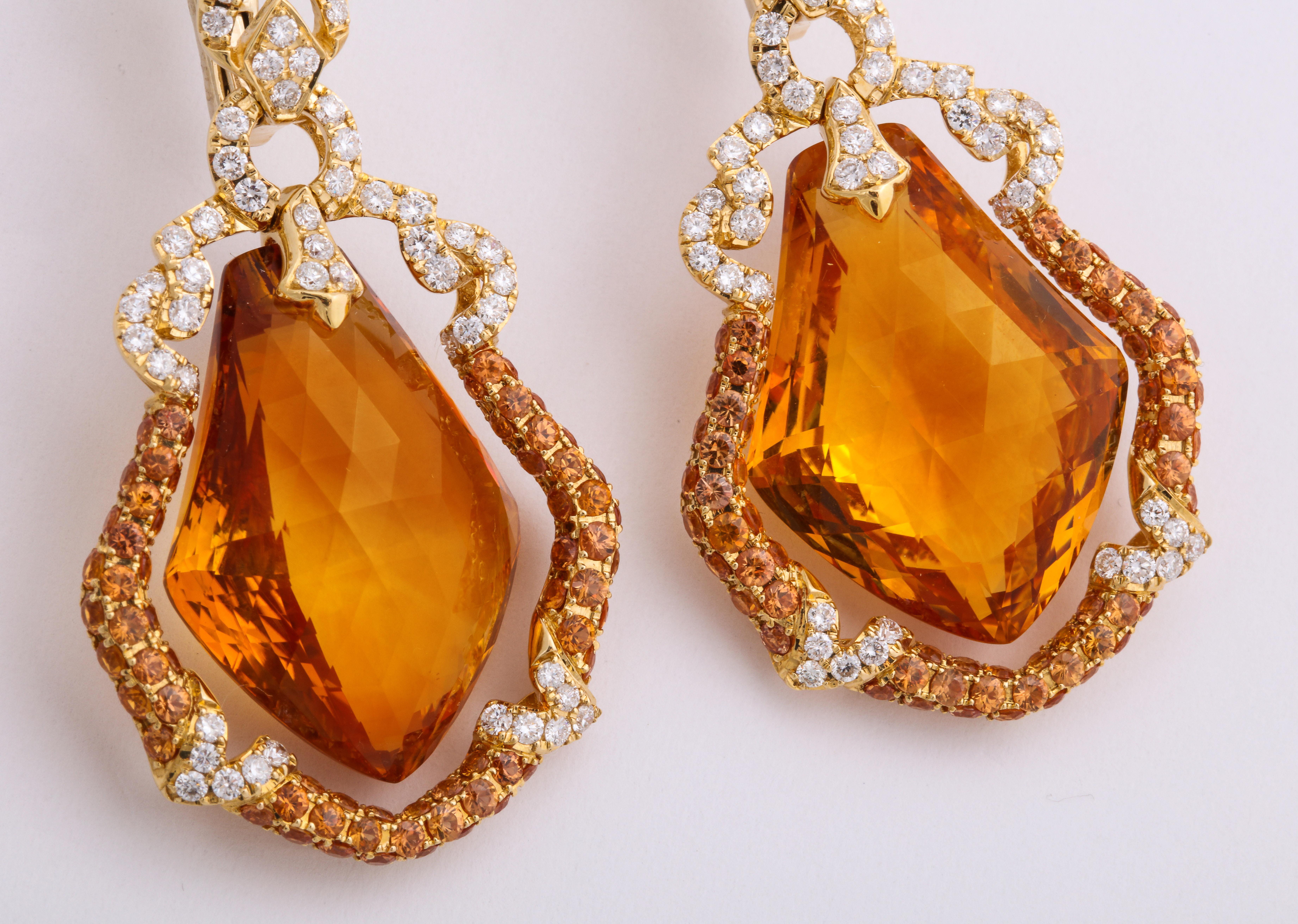 Artistic 18K yellow gold earrings decorated with colorless round brilliant-diamonds: 1.67 carats, suspending kite-shape, briolette honey-color citrine: 51.76 carats, within a frame of pave'-set, diamond-cut orange sapphires: 3.47 carats.
French
