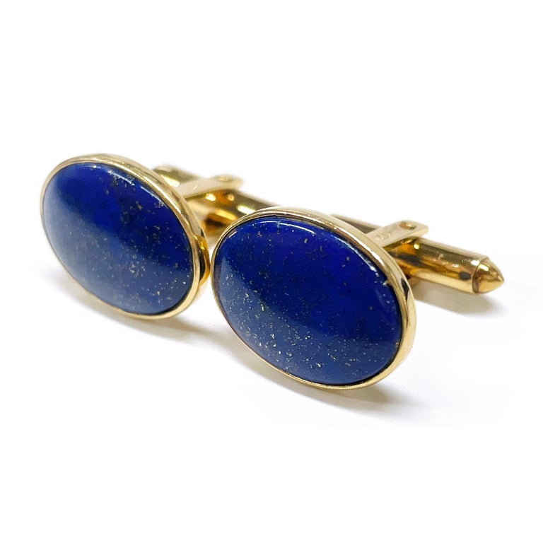 14 Karat Yellow Gold Lapis Lazuli Cufflinks. The cufflinks consist of an oval cabochon of Lapis Lazuli showing natural pyrite, a dual post, and torpedo toggle backings. The cufflink fronts measure approximately 19.5mm x 14.5mm. Stamped on the dual